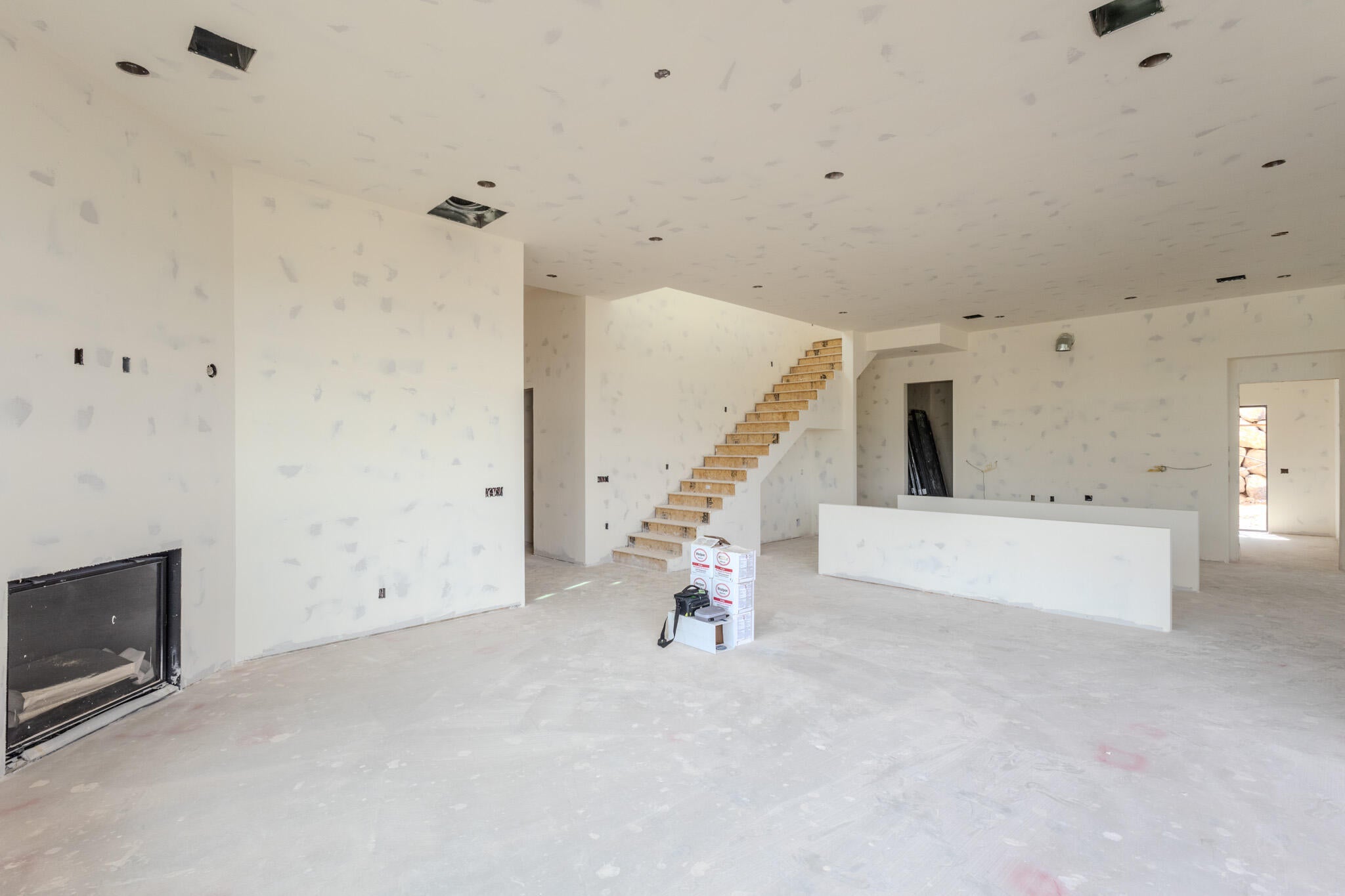 Spacious open-concept interior featuring a modern fireplace, exposed wooden staircase, and recessed lighting