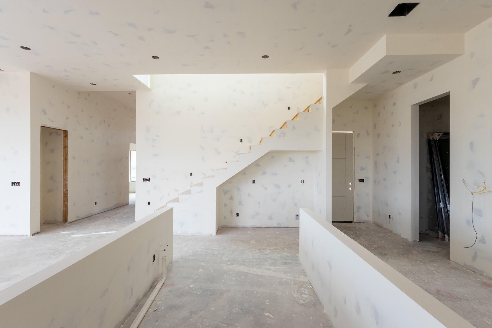 Two-story foyer featuring an open-riser staircase with wood treads, high ceilings, recessed lighting, and a neutral color palette
