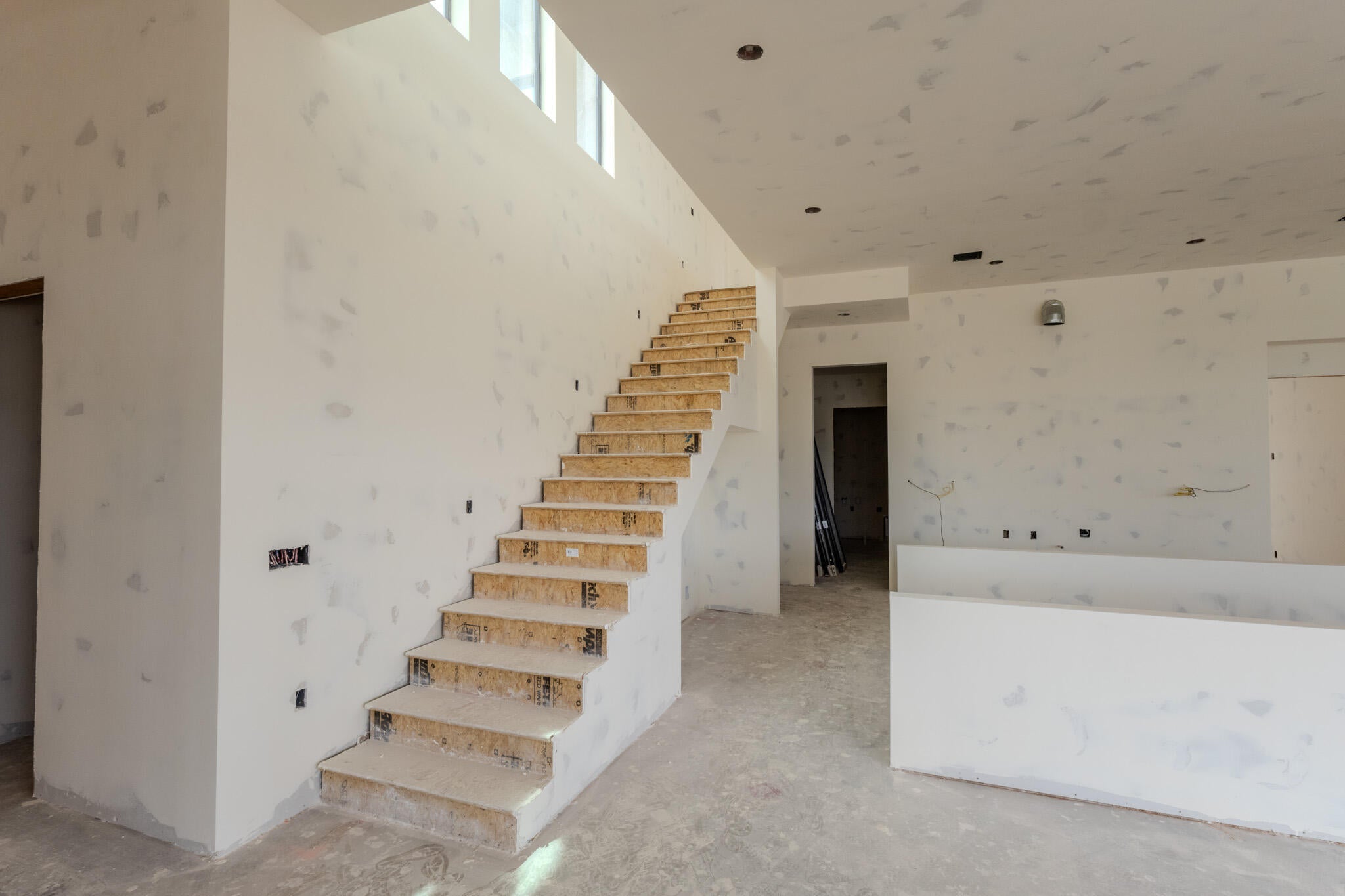 Expansive interior featuring an open-tread staircase with high ceilings and transom windows