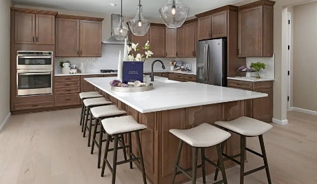 Picture of a similar model only. Not actual home. Actual home will have different finishes or options than seen here Spacious kitchen featuring a large central island with seating, warm wood cabinetry, stainless steel appliances, and wood-finish flooring