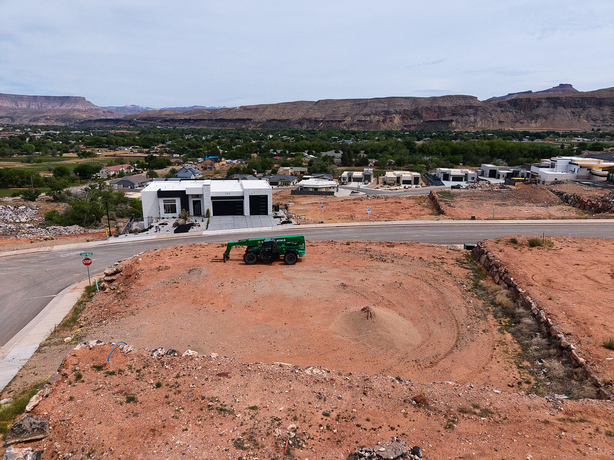 Expansive undeveloped lot featuring red earth terrain, a mound of sand, and a partial retaining wall
