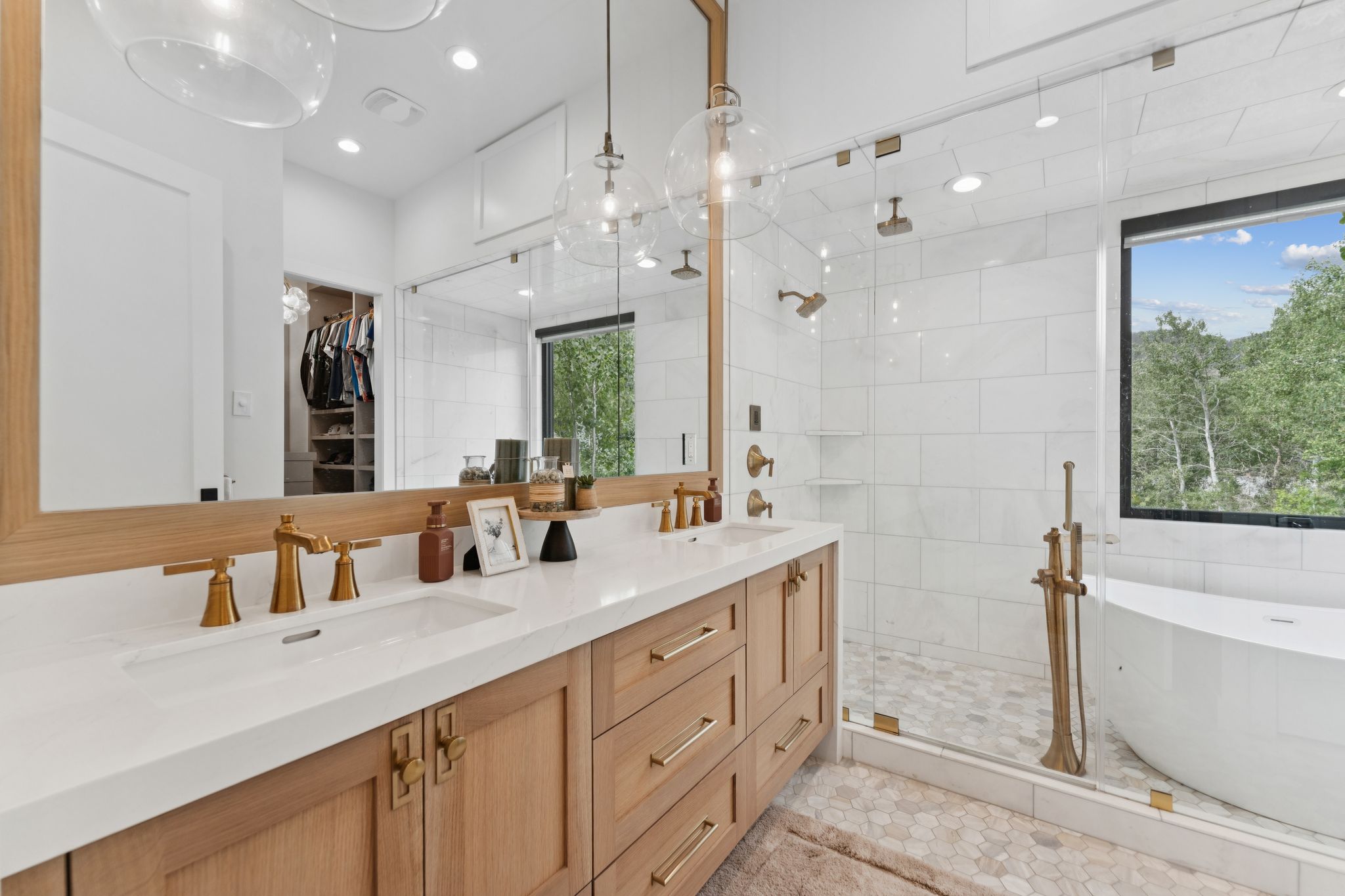 Double vanity featuring light wood-finish cabinetry, white countertops, and brass-tone fixtures