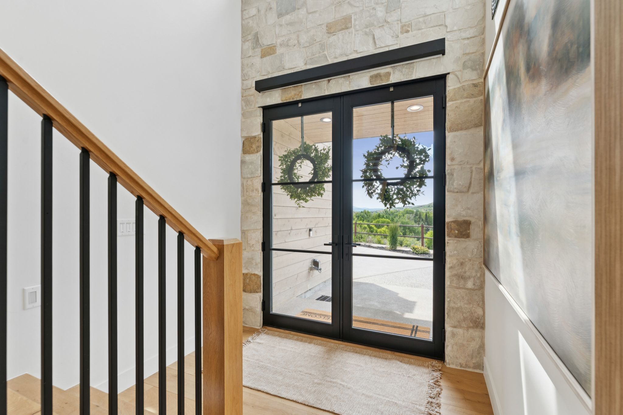 Double black-framed glass entry doors with transom, set within a natural stone wall