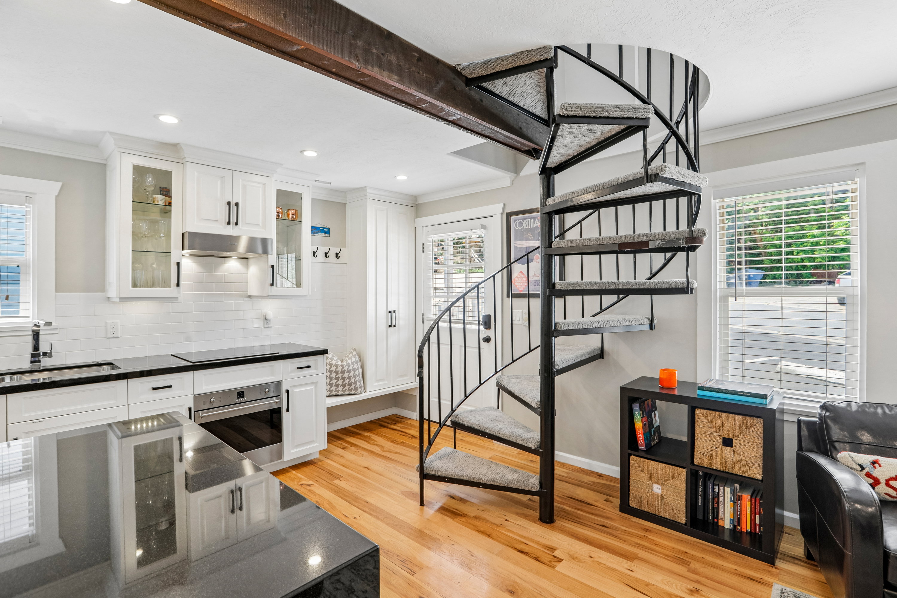 Contemporary spiral staircase with carpeted treads and an exposed wood beam