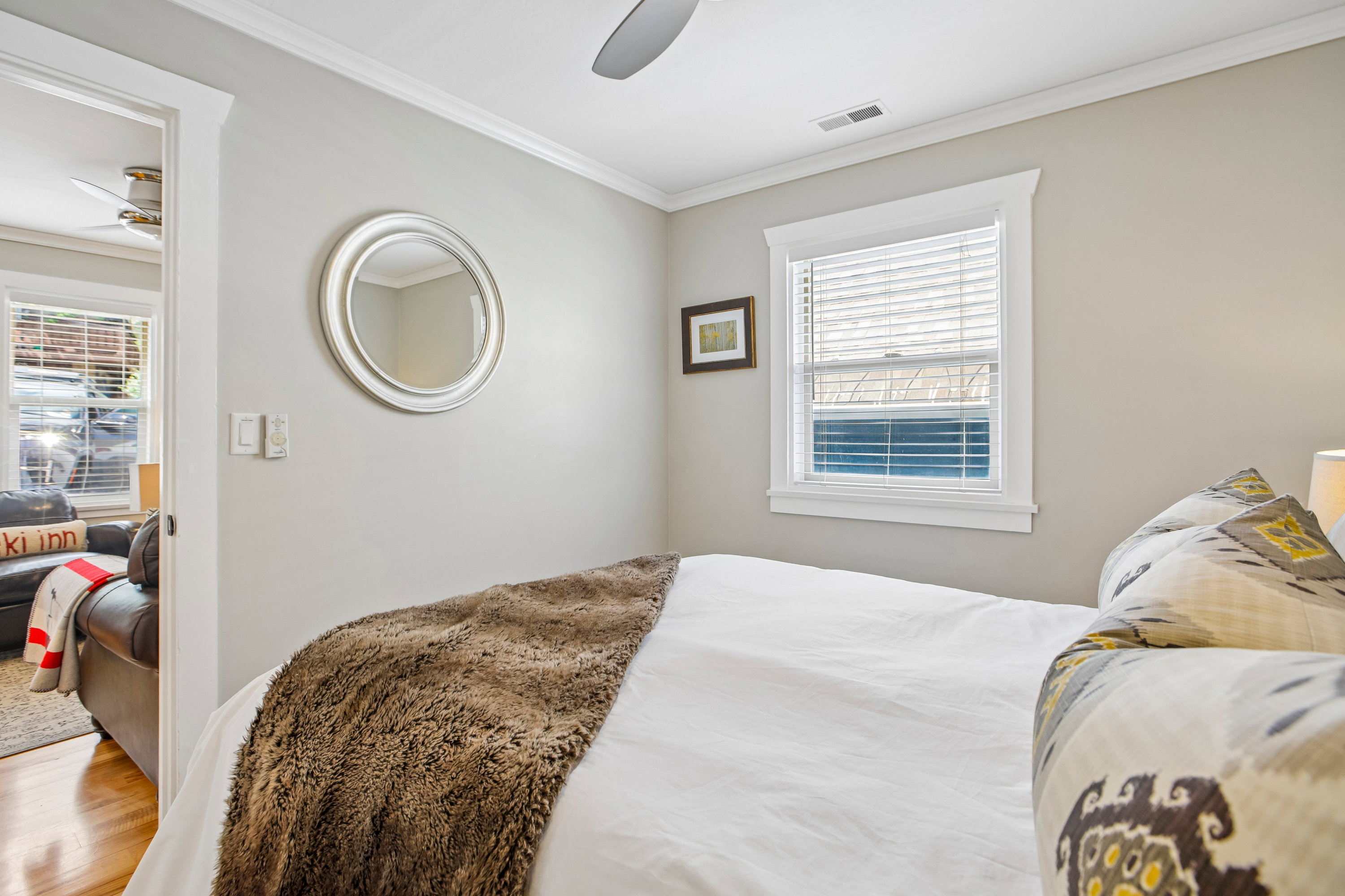 Bedroom featuring crown molding, a window with blinds, and wood-finish flooring visible through the doorway