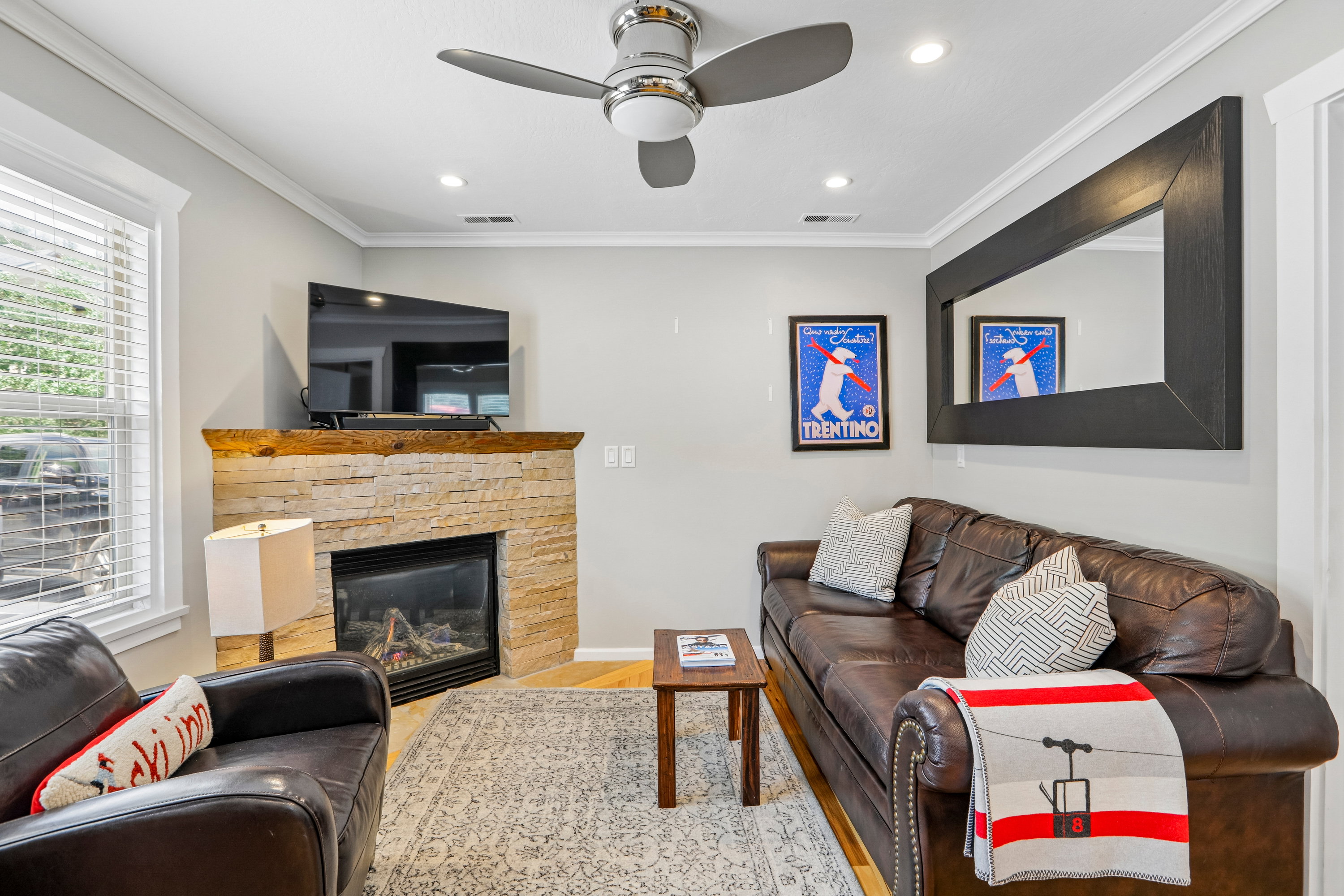Living area featuring a stone-clad fireplace with a wood mantel, crown molding, and recessed lighting