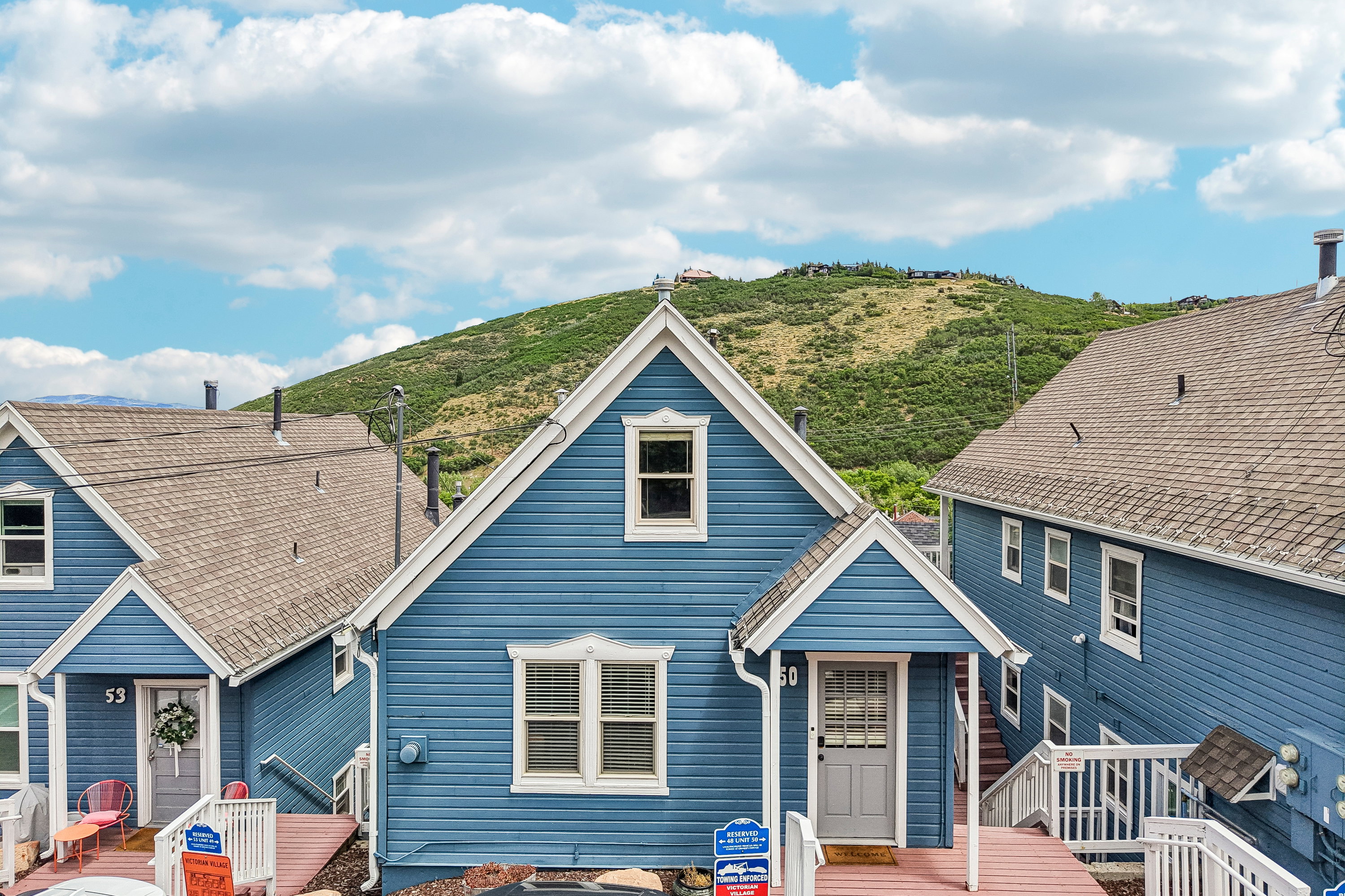 Blue siding property featuring white trim, a gabled roofline, a front porch with an awning, and a prominent mountain backdrop