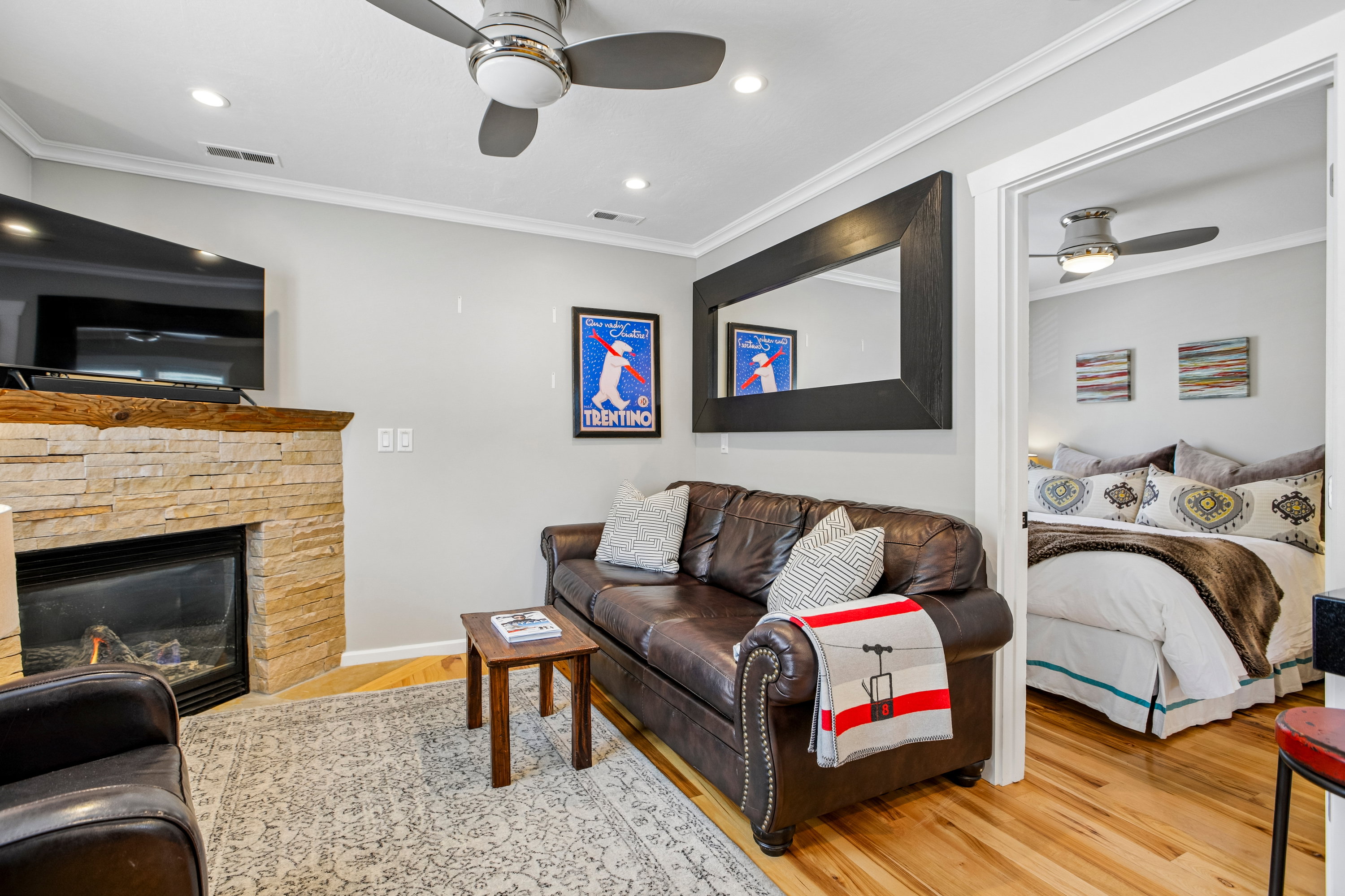 Living area featuring a stone-clad fireplace with a wood mantel, recessed ceiling lighting, and wood-finish flooring