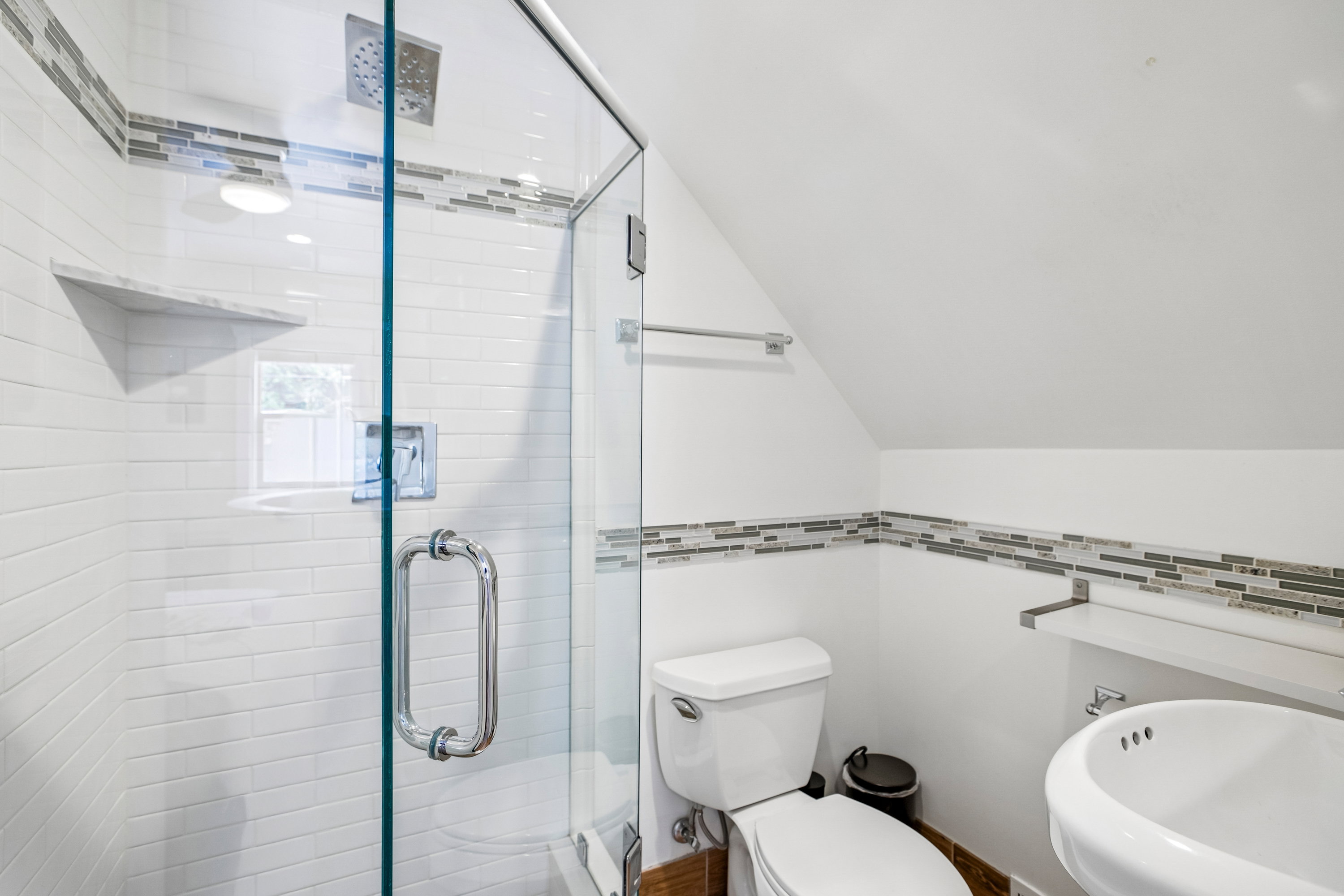 Contemporary bathroom featuring a glass-enclosed shower with subway tile surround and a built-in shelf