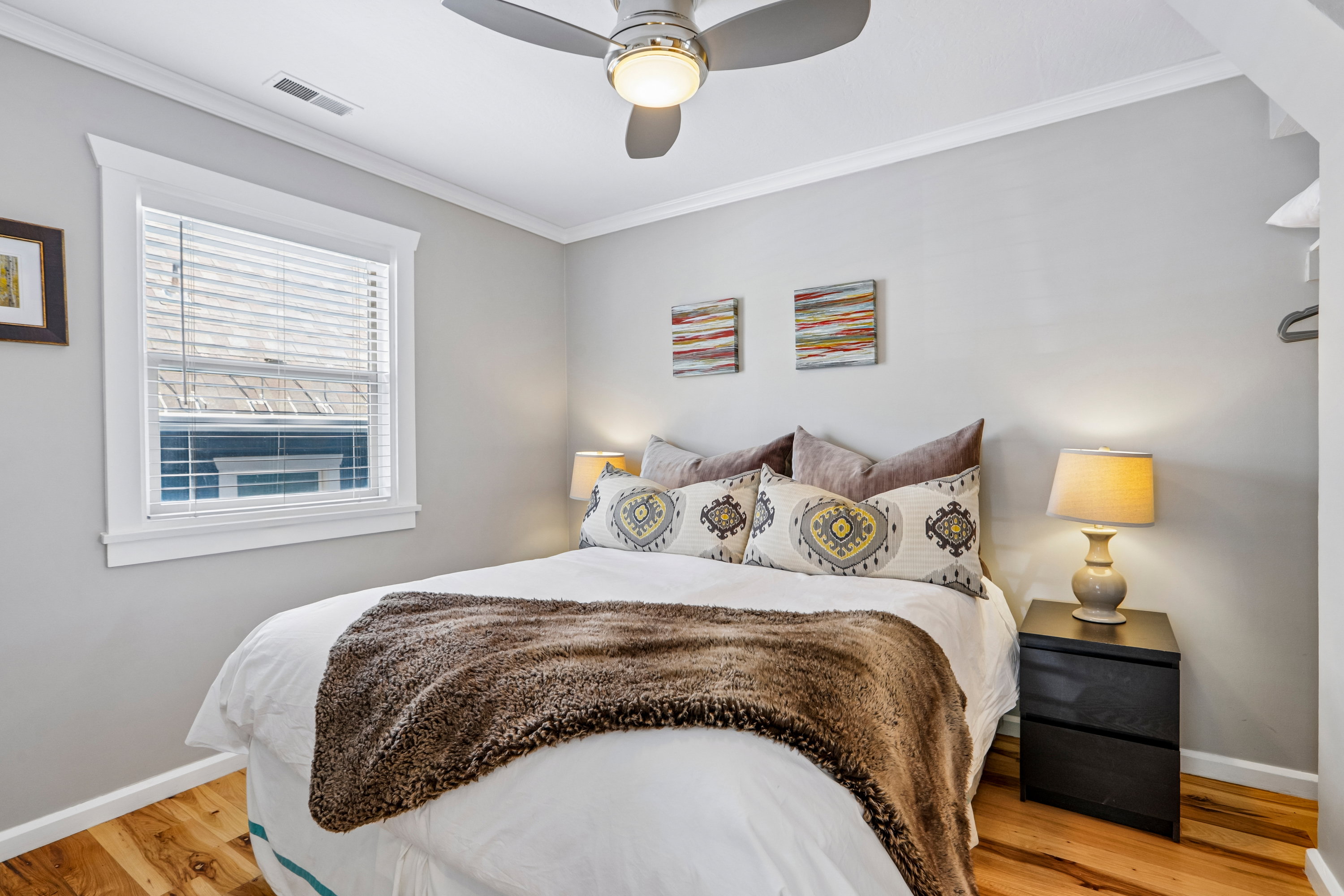 Light-filled room featuring wood-finish flooring, a window with blinds, and white trim