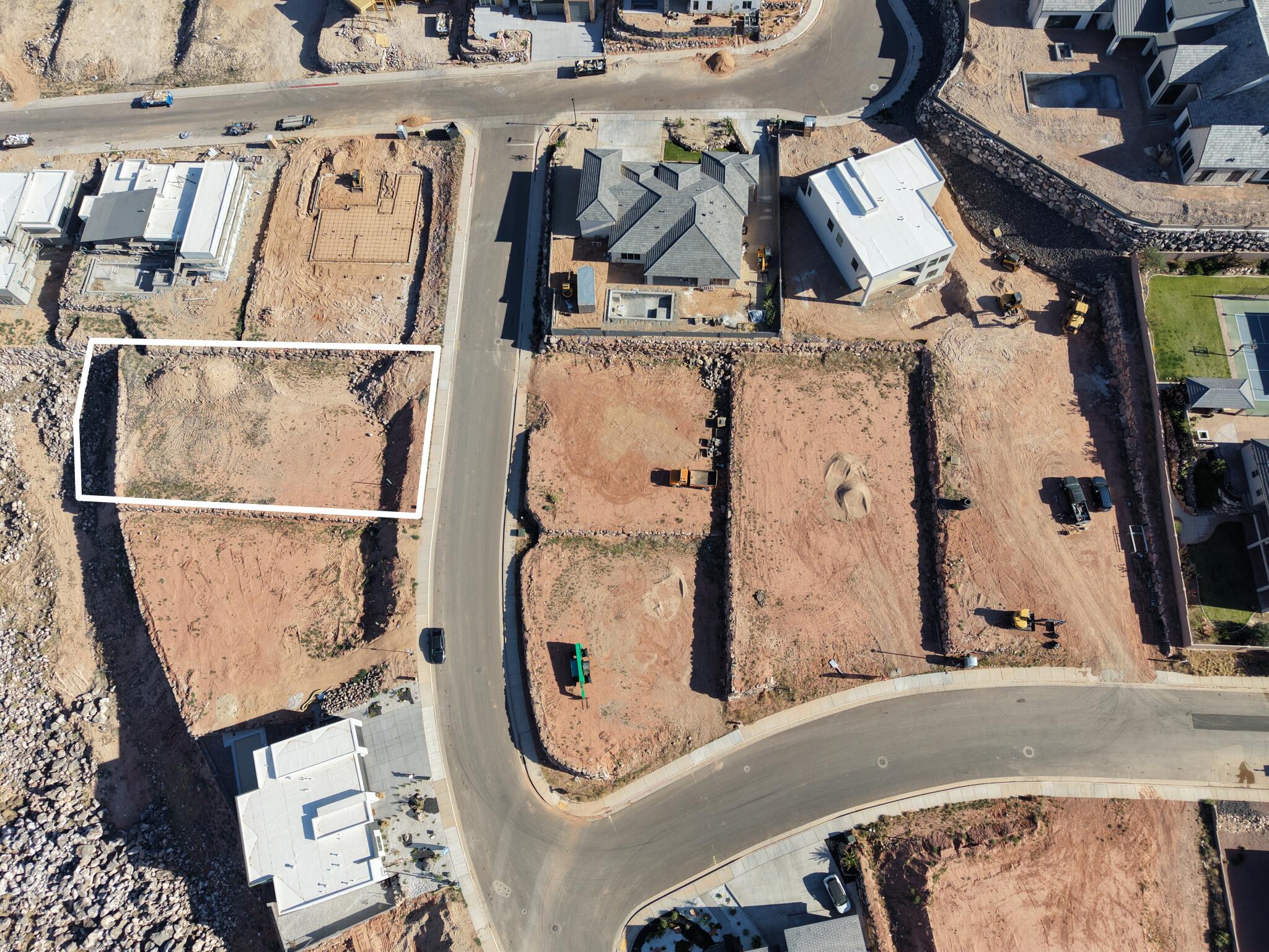 Aerial view of a rectangular lot, bordered by a paved road and retaining walls