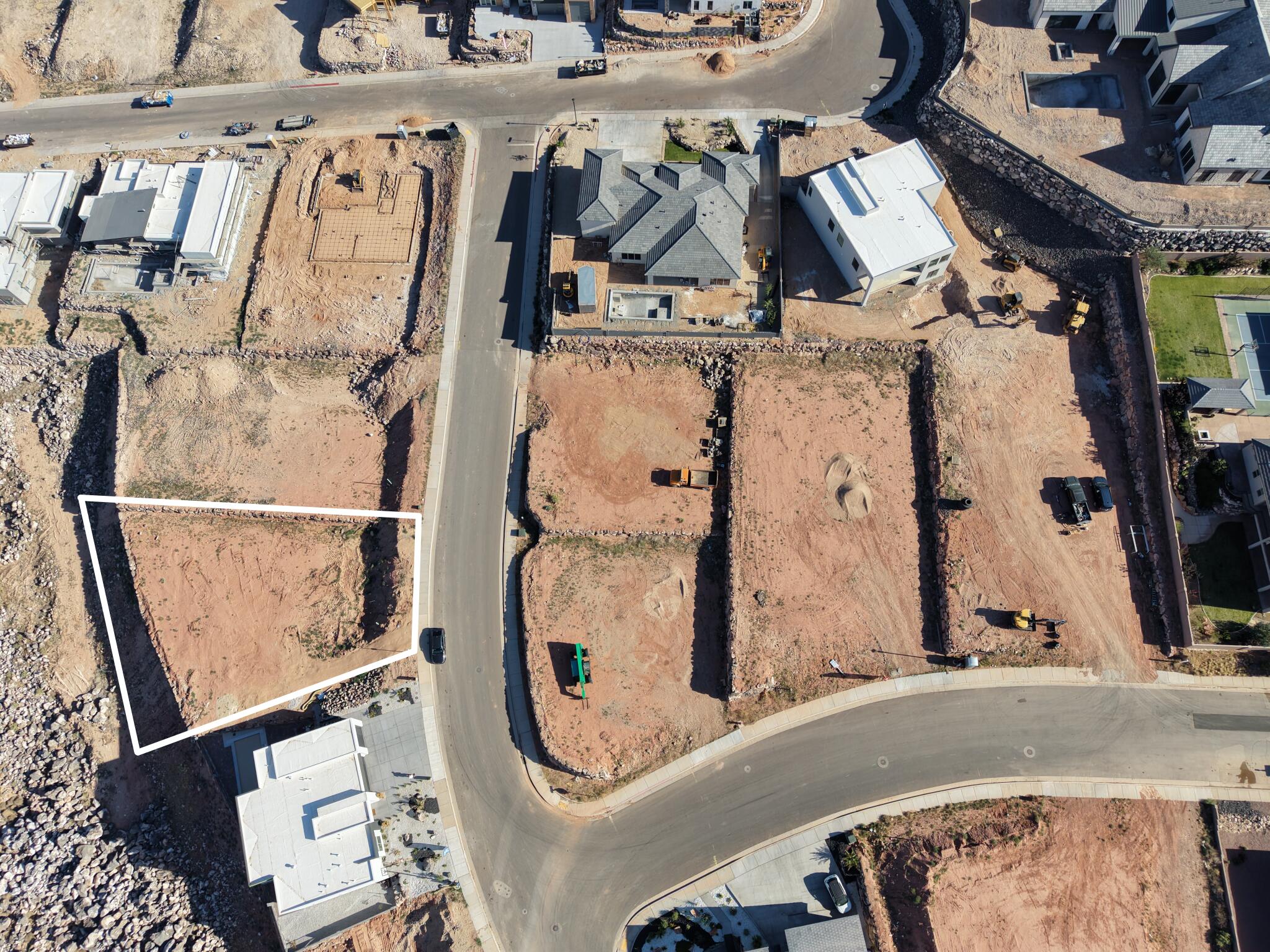 Vacant parcel with clear lot boundaries, surrounded by residential development, featuring a curvilinear street system