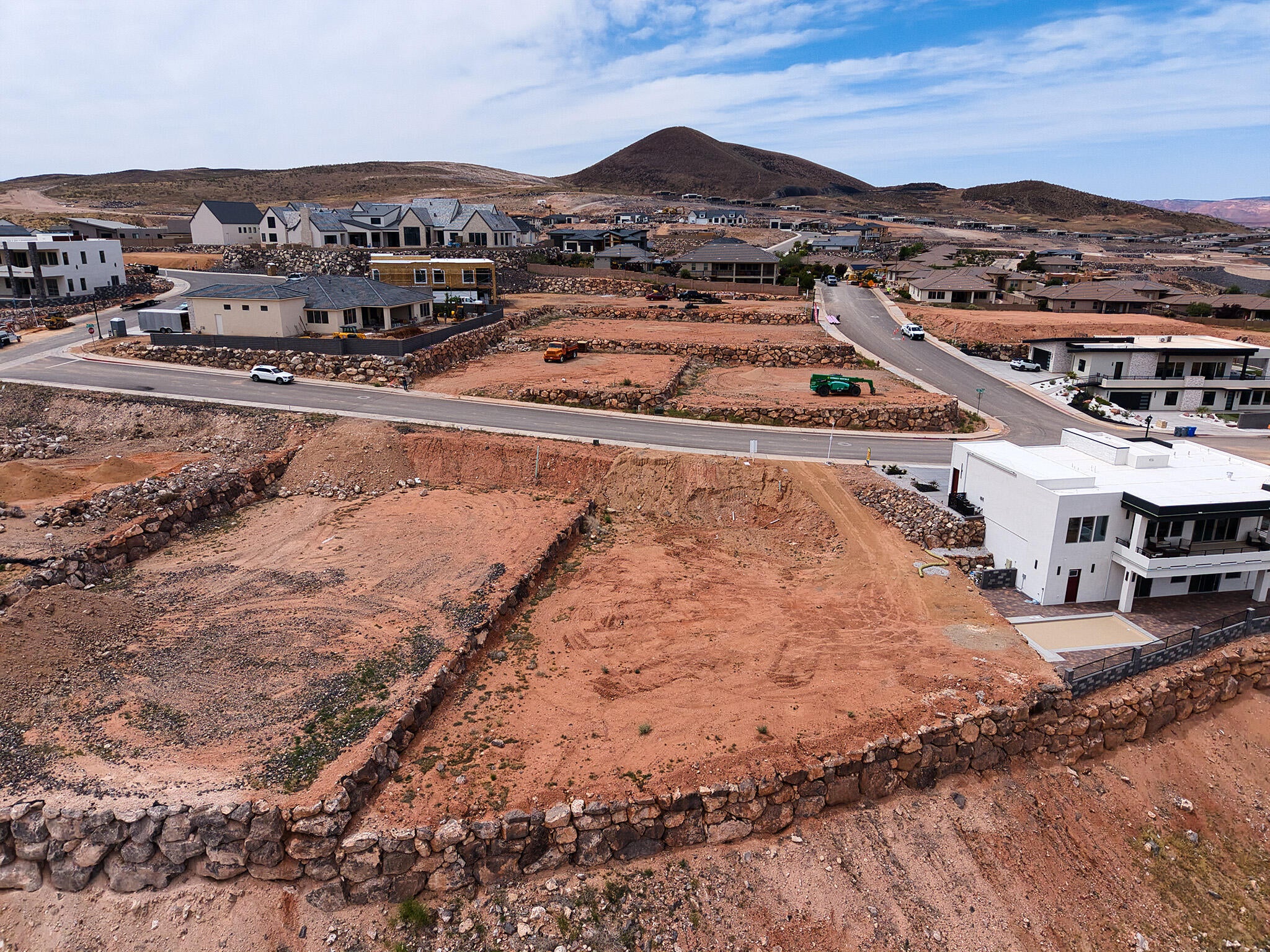Graded lot featuring a retaining wall, surrounded by developed residential properties and distant mountainous terrain