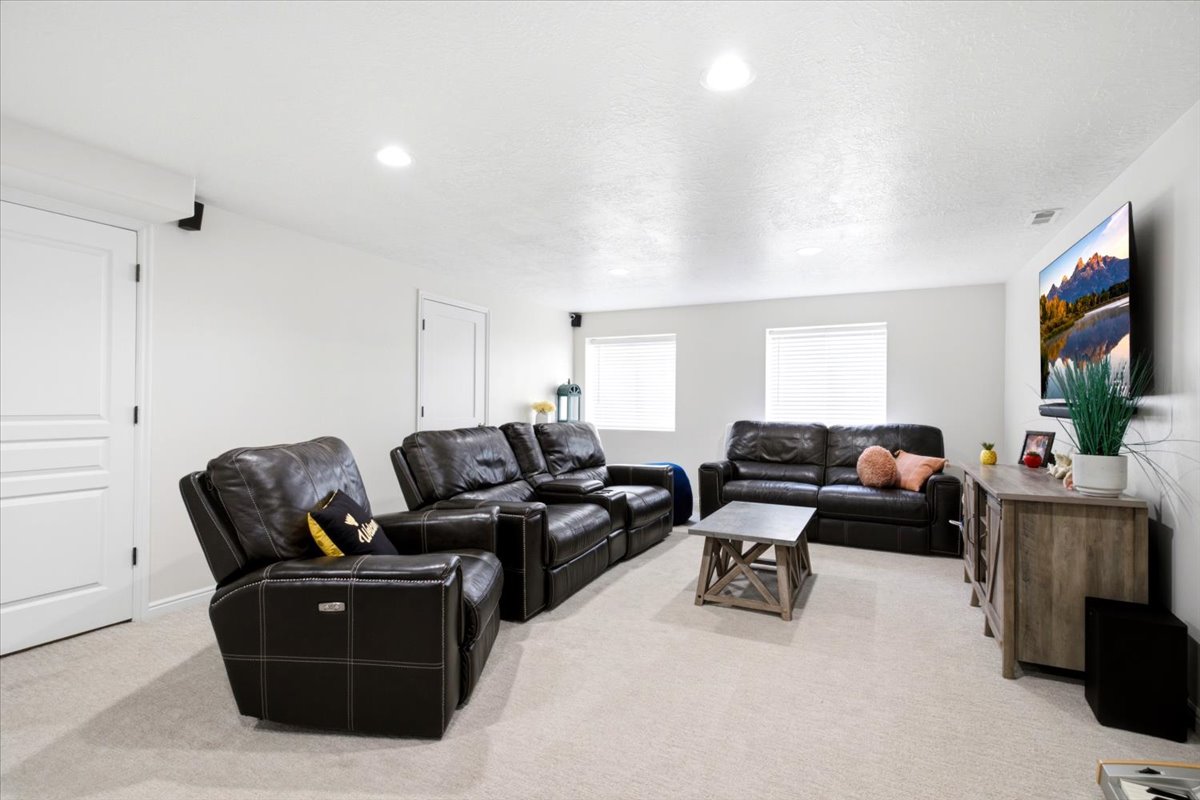 Spacious entertainment area featuring light-toned carpeting and recessed ceiling lighting