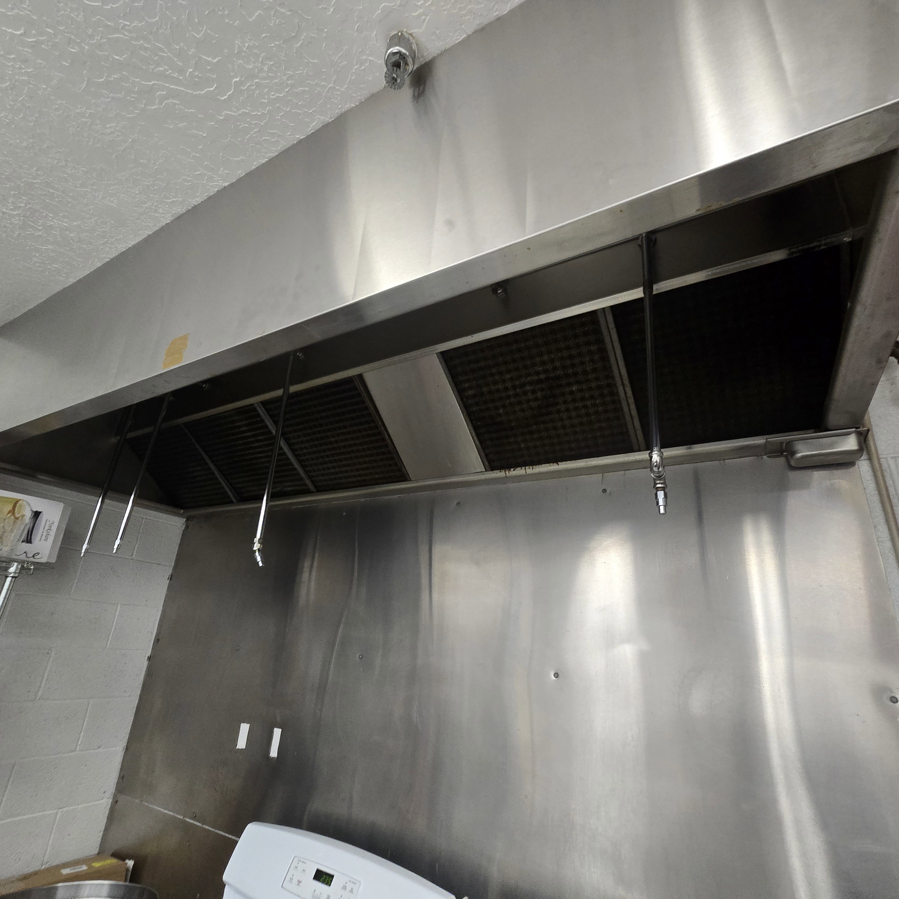 Stainless steel commercial-grade exhaust hood with integrated fire suppression system and baffle filters