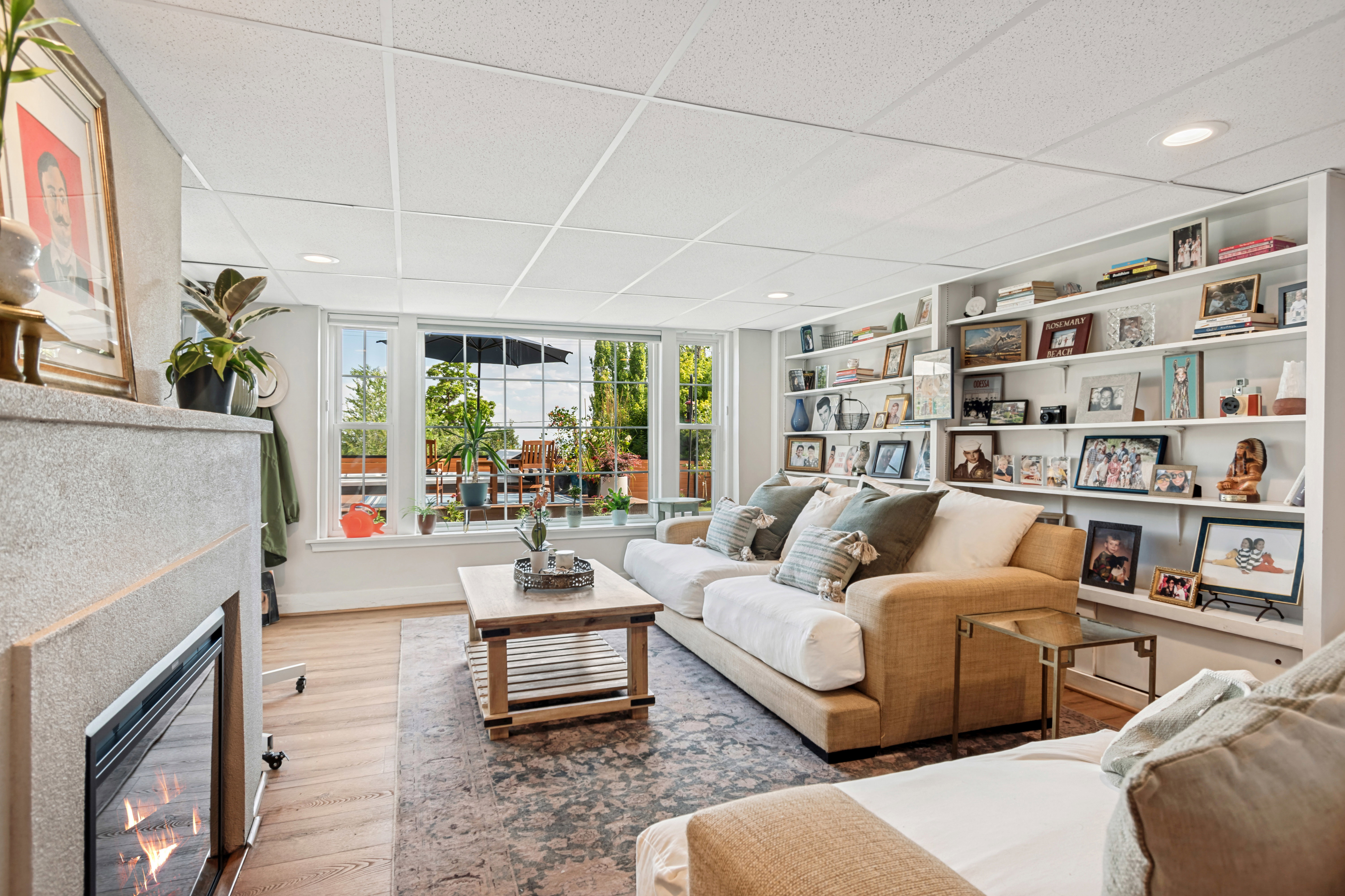 Spacious living area featuring a built-in fireplace with a stone surround, large windows, recessed lighting, and extensive built-in shelving