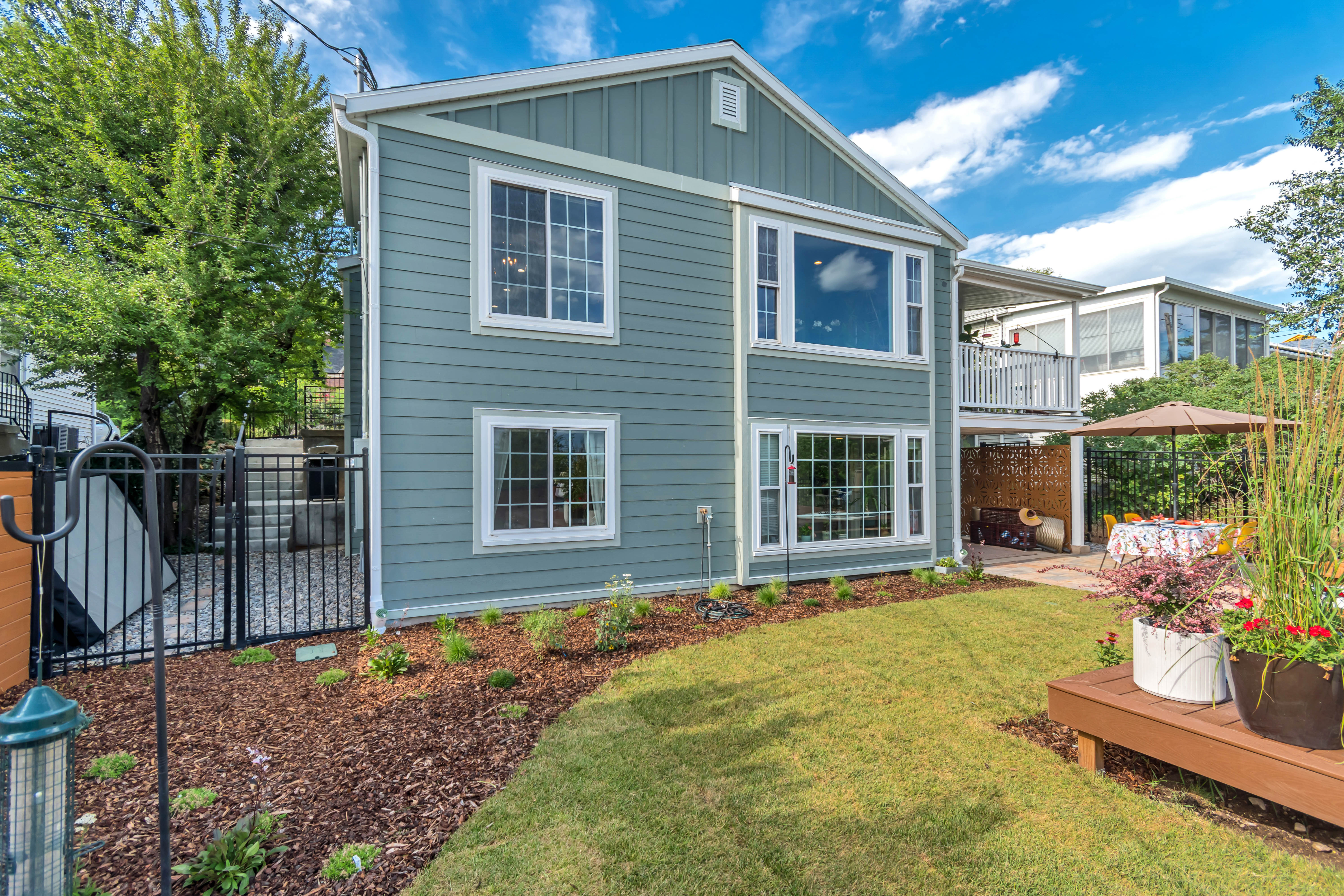 Backyard featuring a manicured lawn, mulched garden beds, and a stone patio