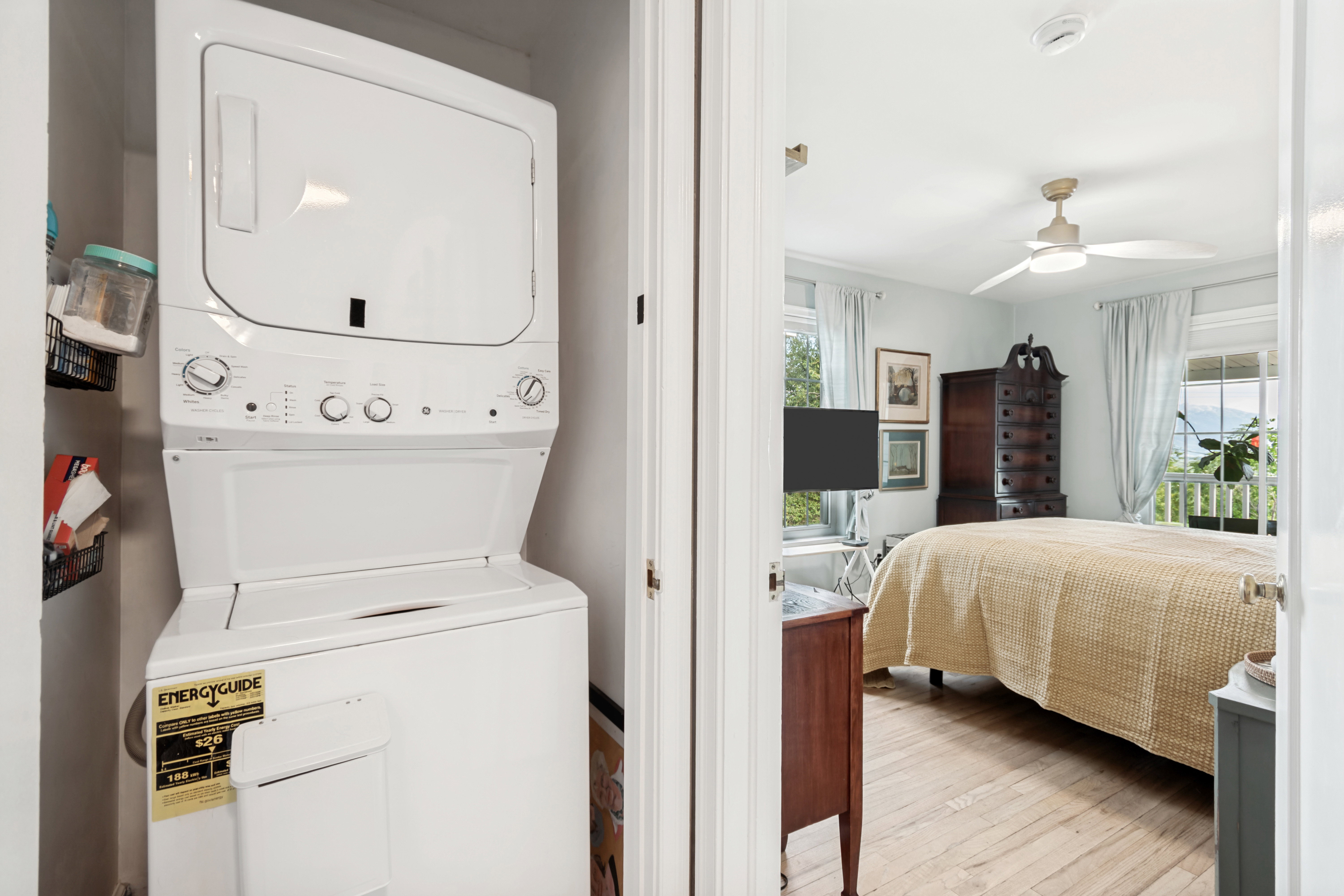 In-unit stacked laundry appliances within a dedicated closet, featuring a white finish