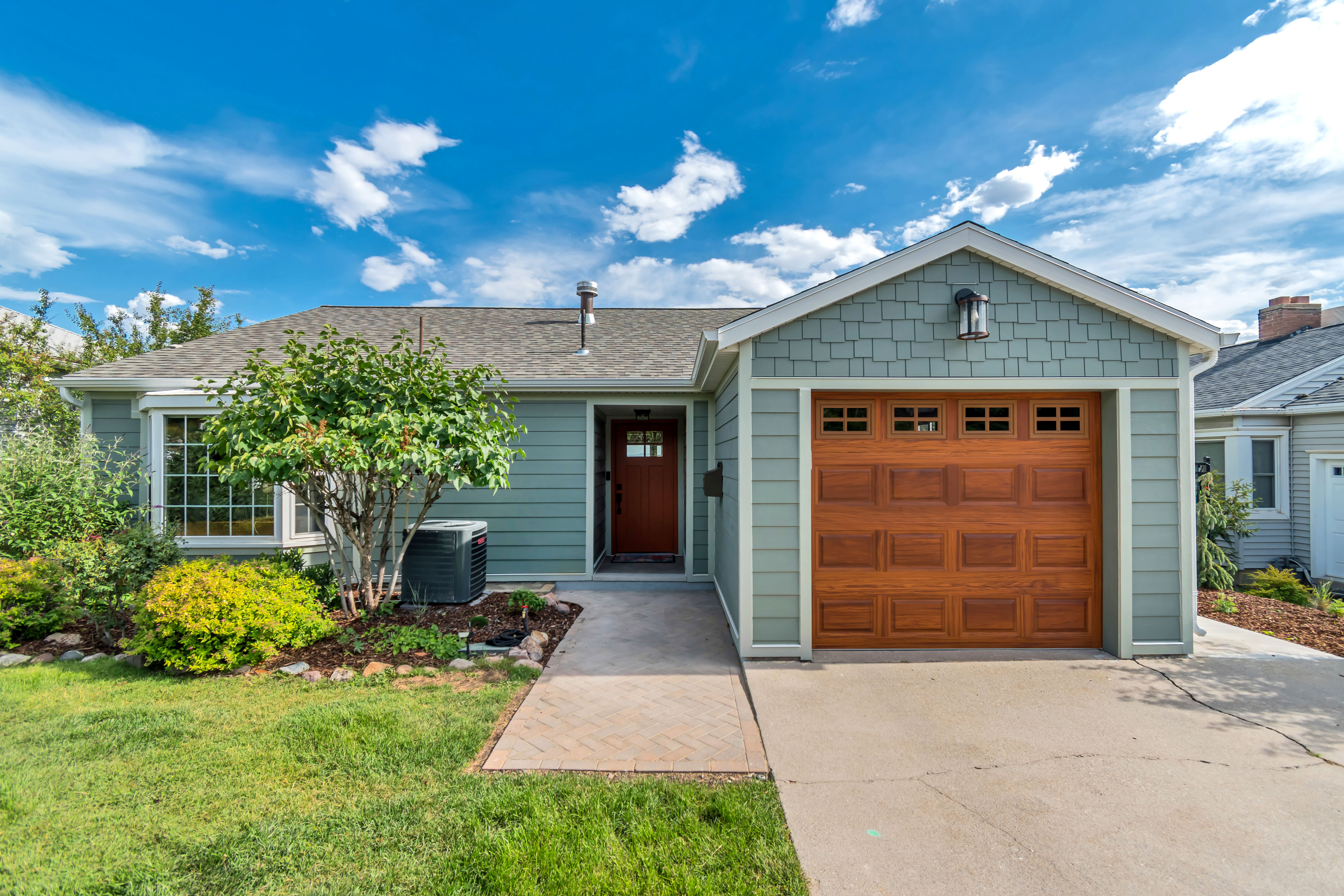 Single-story residence featuring light green siding and a wood-finish garage door with window inserts