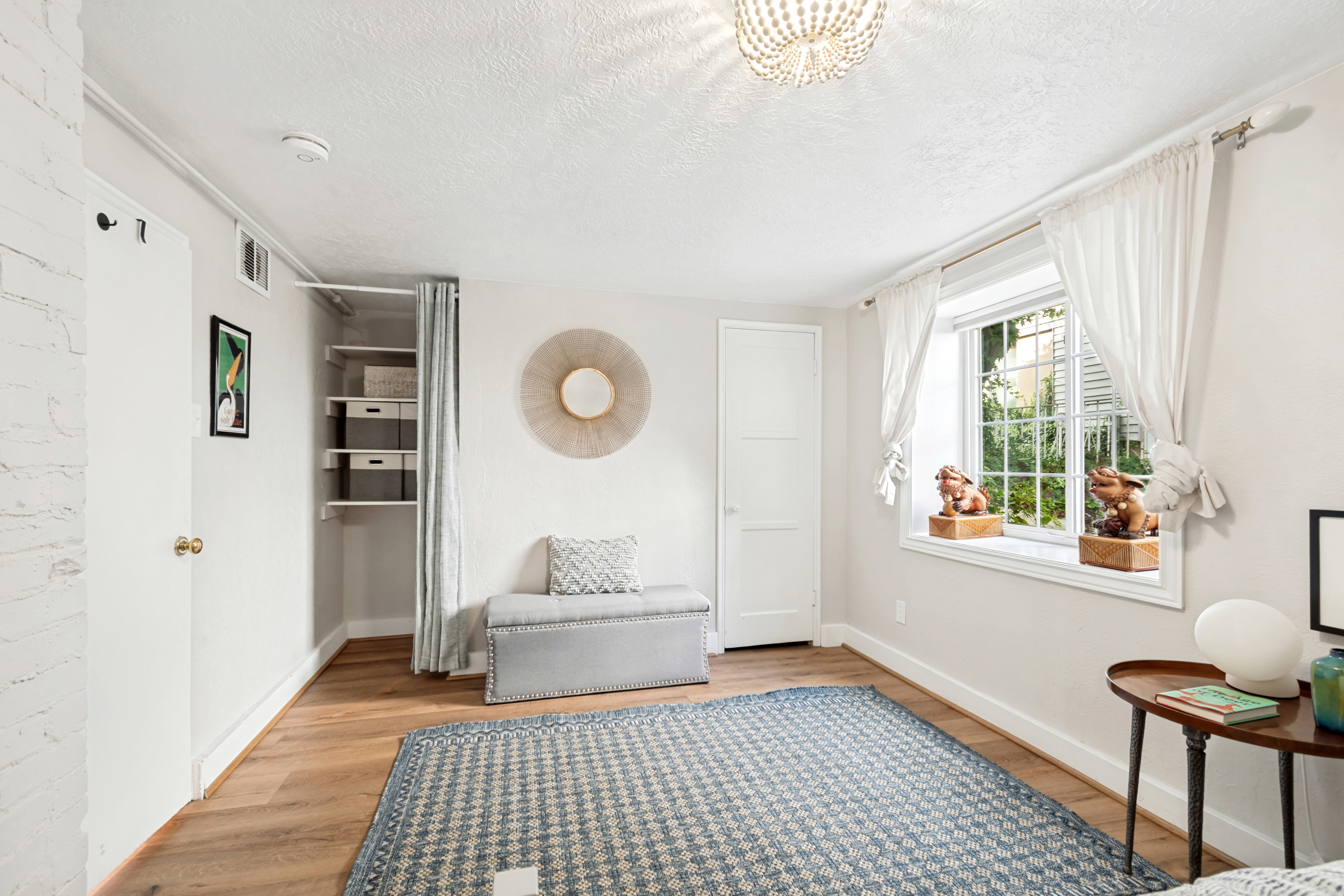Spacious room featuring wood-finish flooring, a large window with white trim, and a ceiling-mounted light fixture