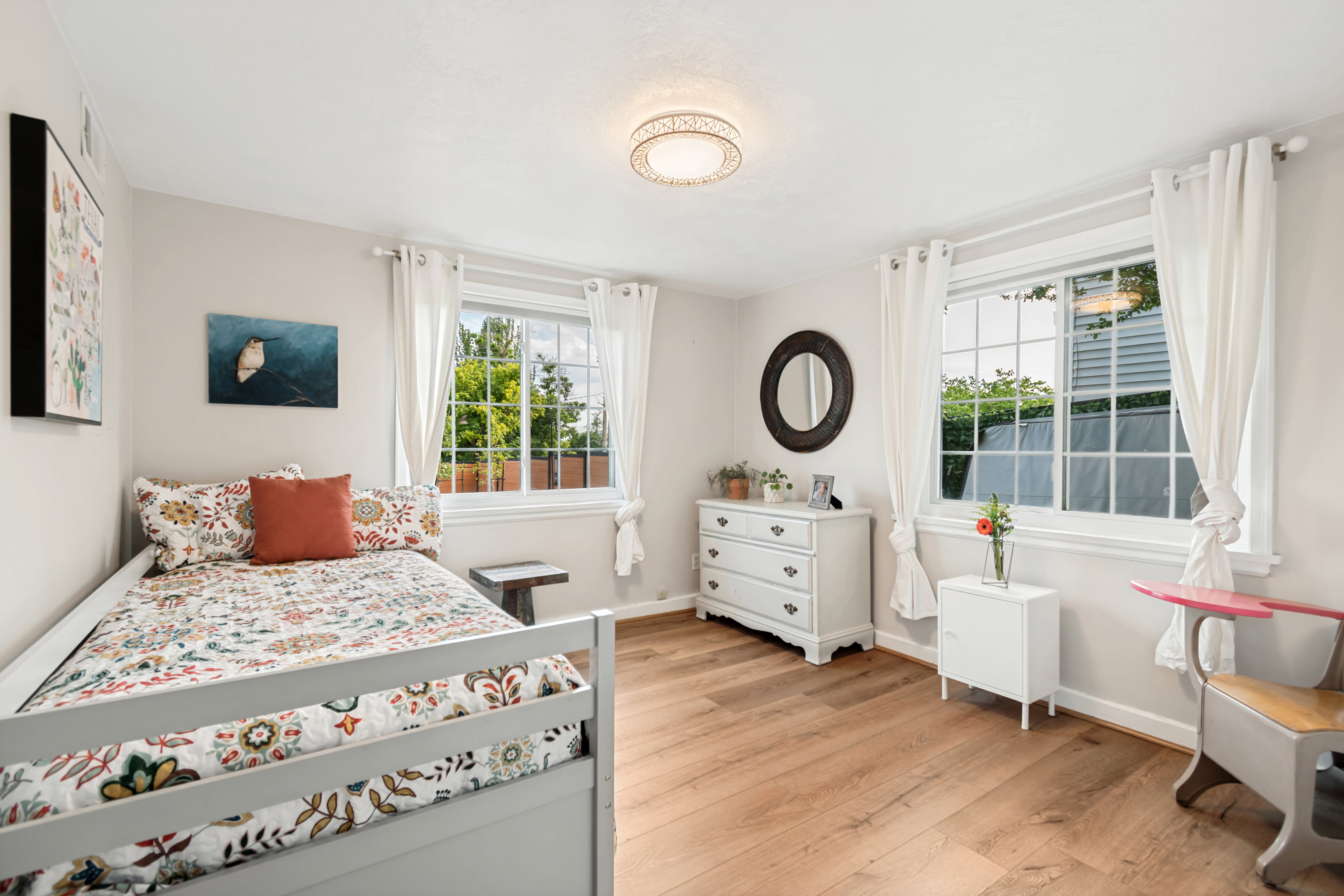 Spacious room featuring wood-finish flooring, light-toned walls, and a decorative ceiling light fixture