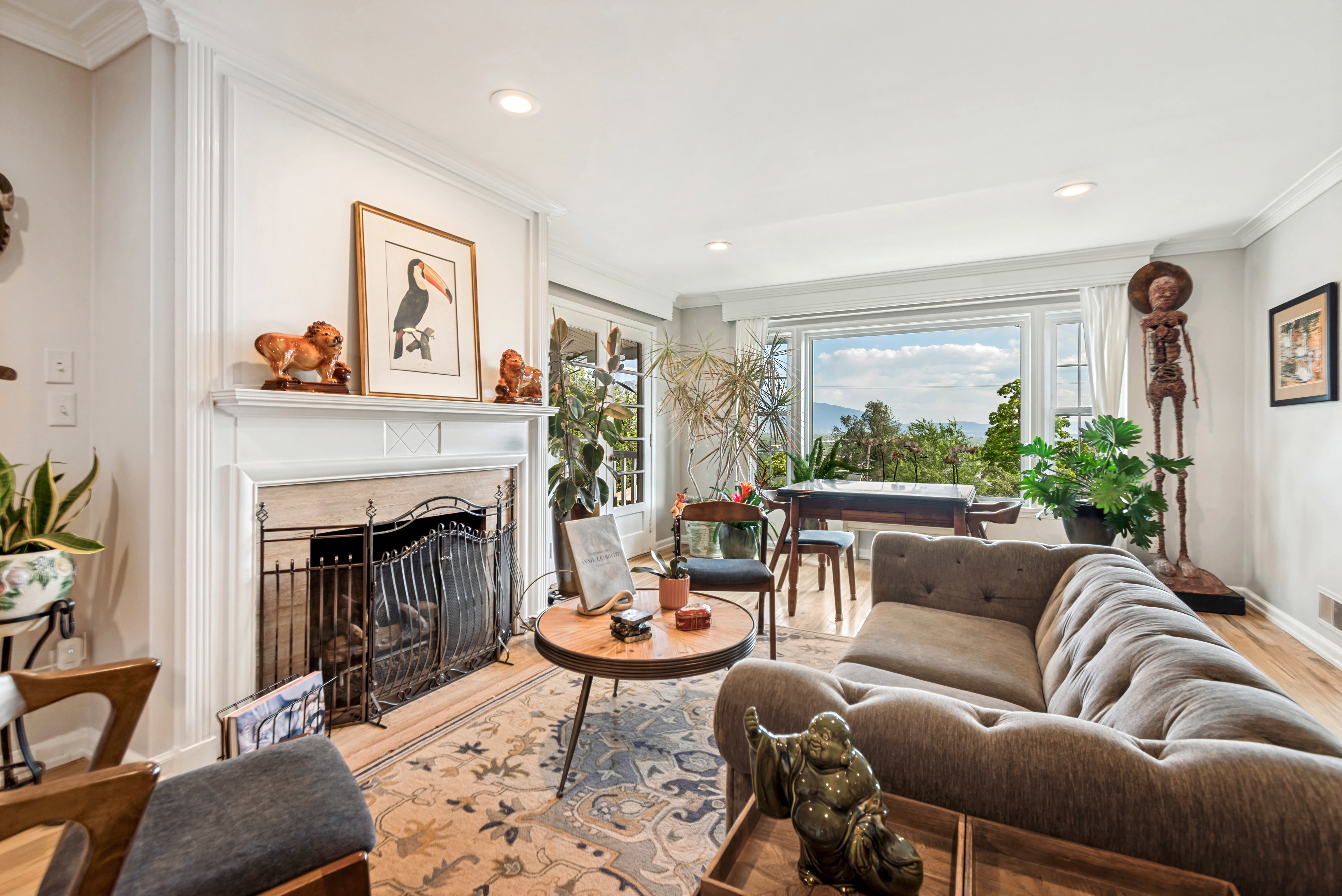 Living area featuring an architectural fireplace with a stone surround and ornate screen, crown molding, recessed lighting, and wood-finish flooring
