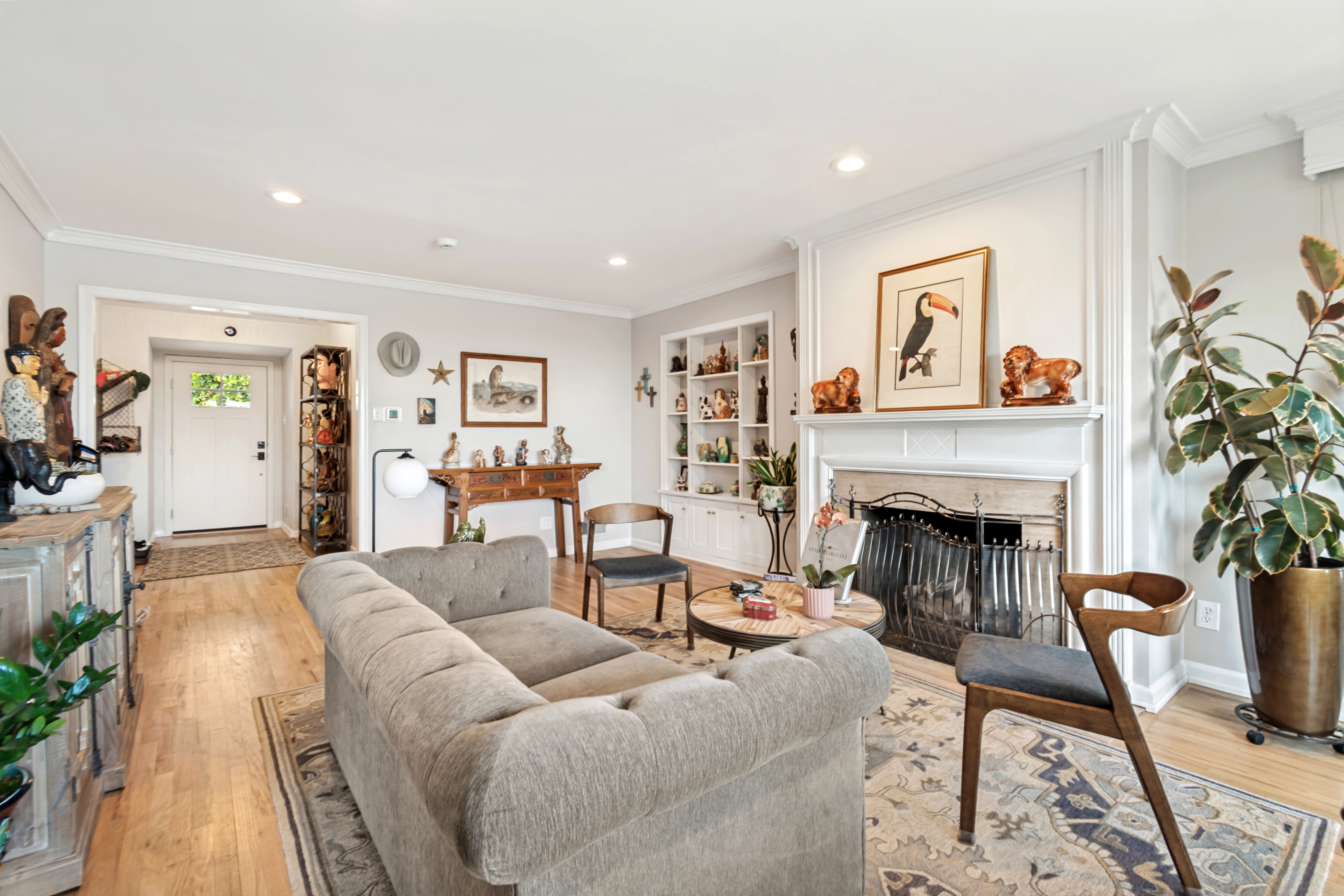 Living area featuring a fireplace with a detailed screen, built-in shelving, hardwood flooring, recessed lighting, and crown molding