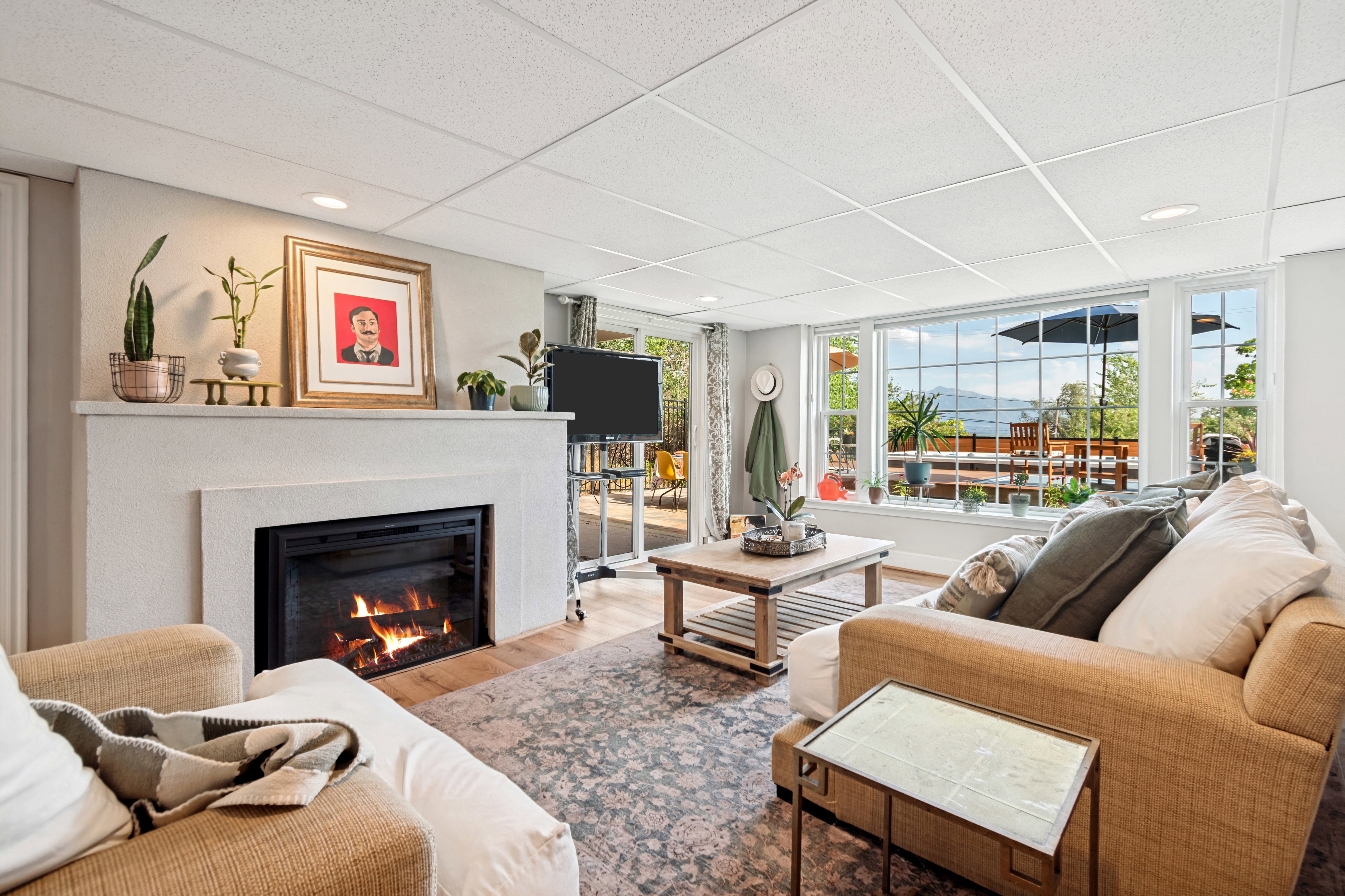 Spacious living area featuring a prominent fireplace, large windows, wood-finish flooring, and recessed lighting