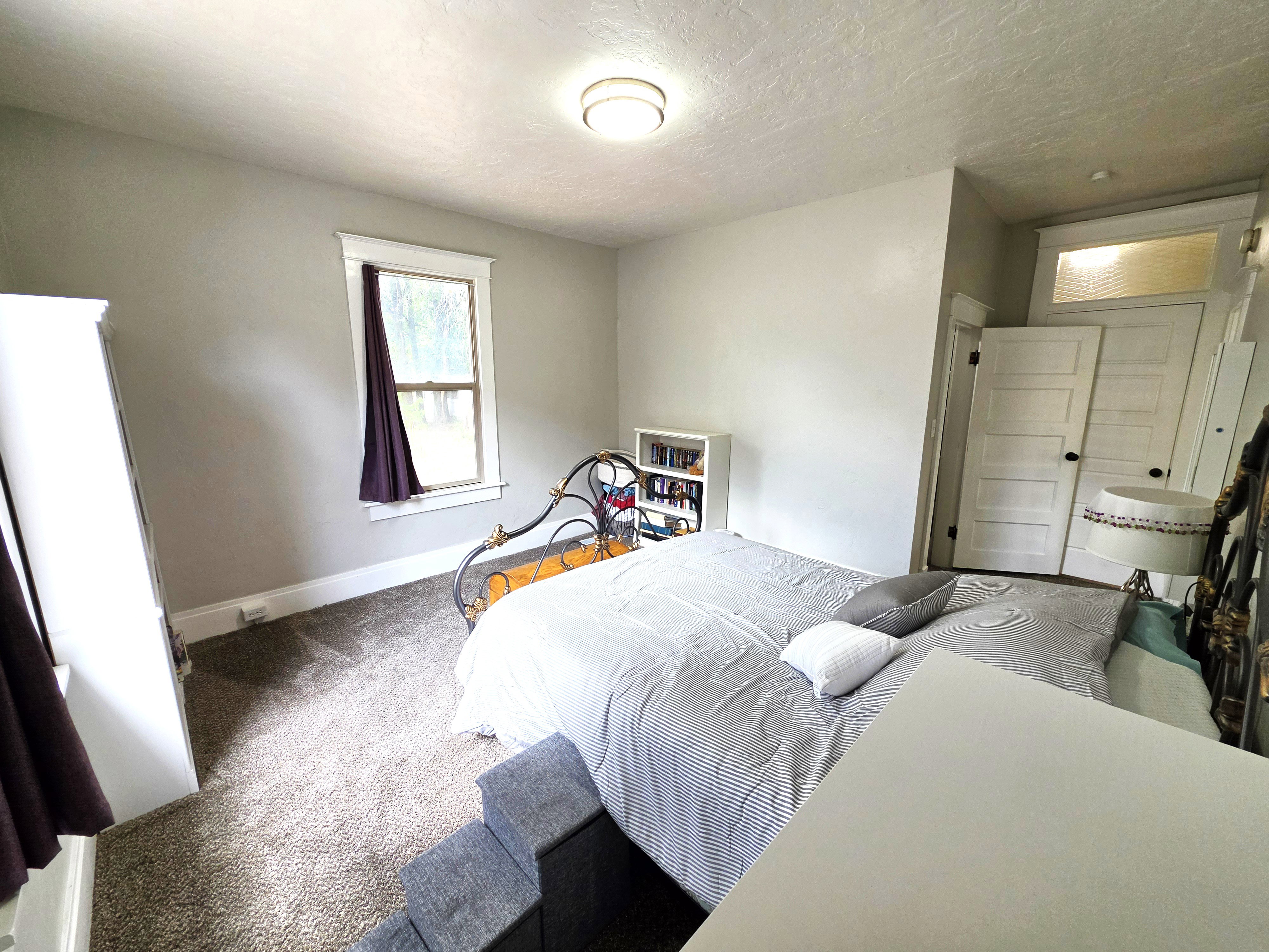 Light-filled room featuring a single window with white trim, gray wall paint, and gray carpet flooring