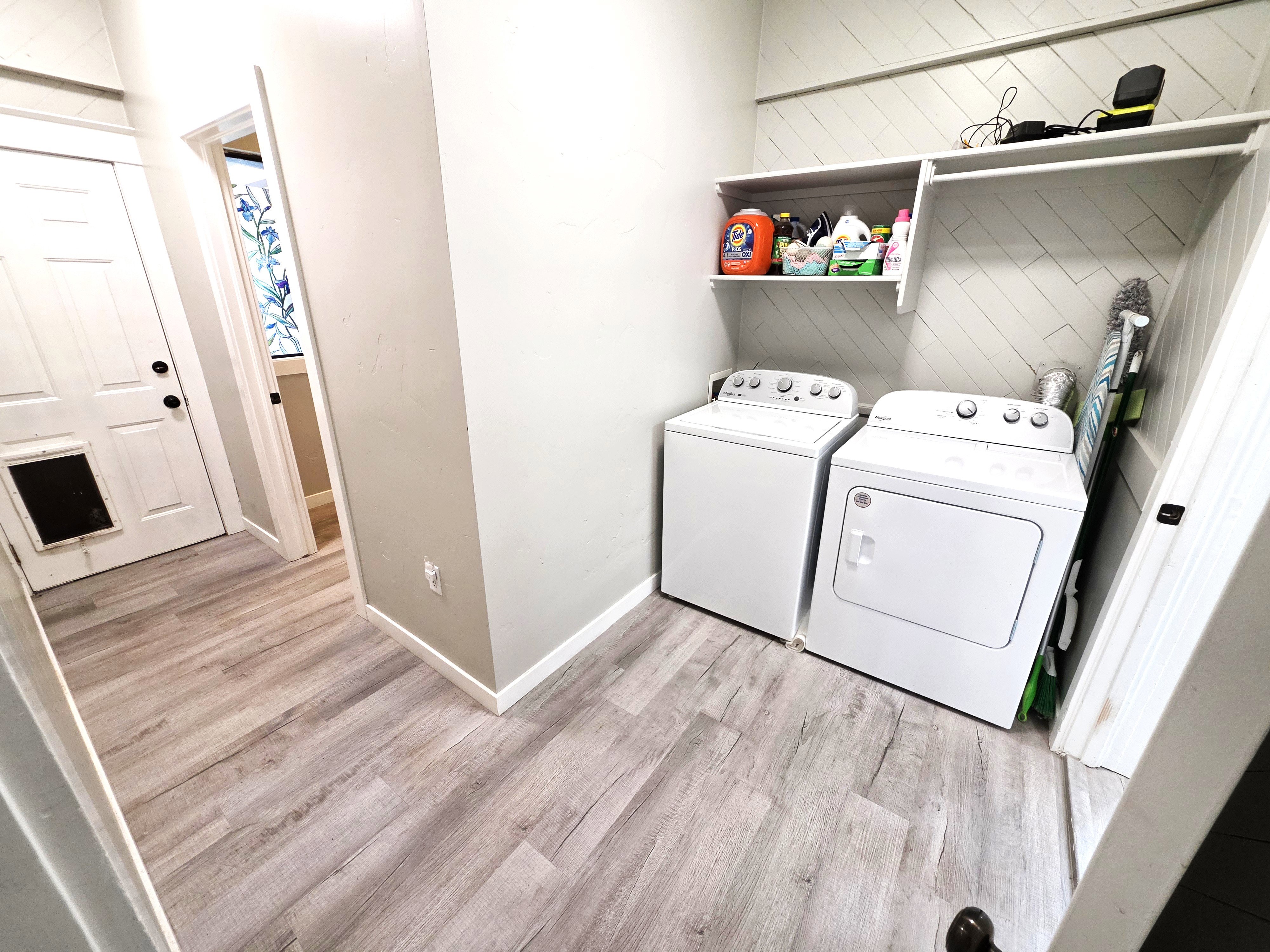 Dedicated laundry area featuring a washer and dryer, wood-finish flooring, and built-in shelving