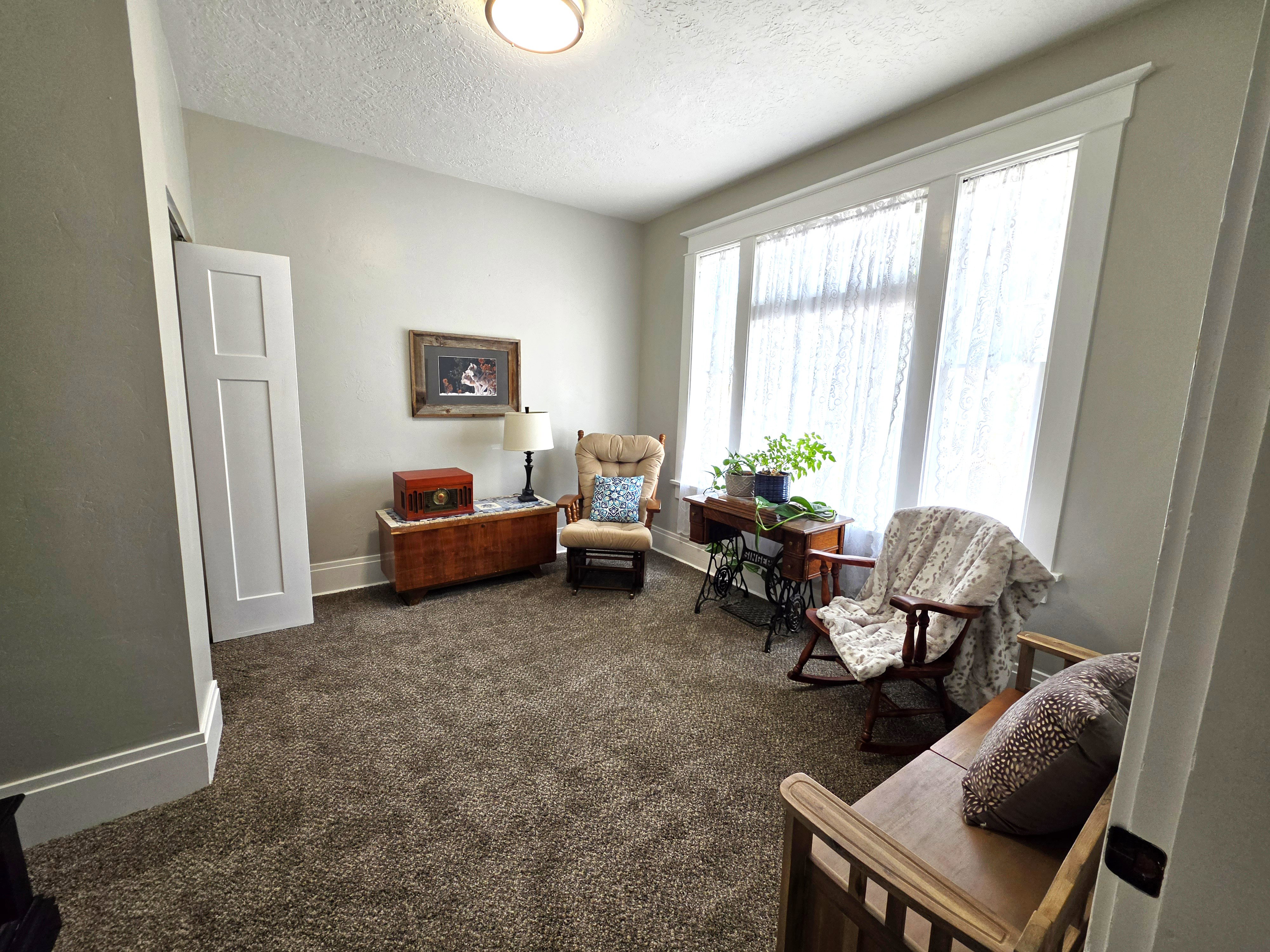 Room featuring light gray walls, textured carpeting, and a three-panel window with white trim