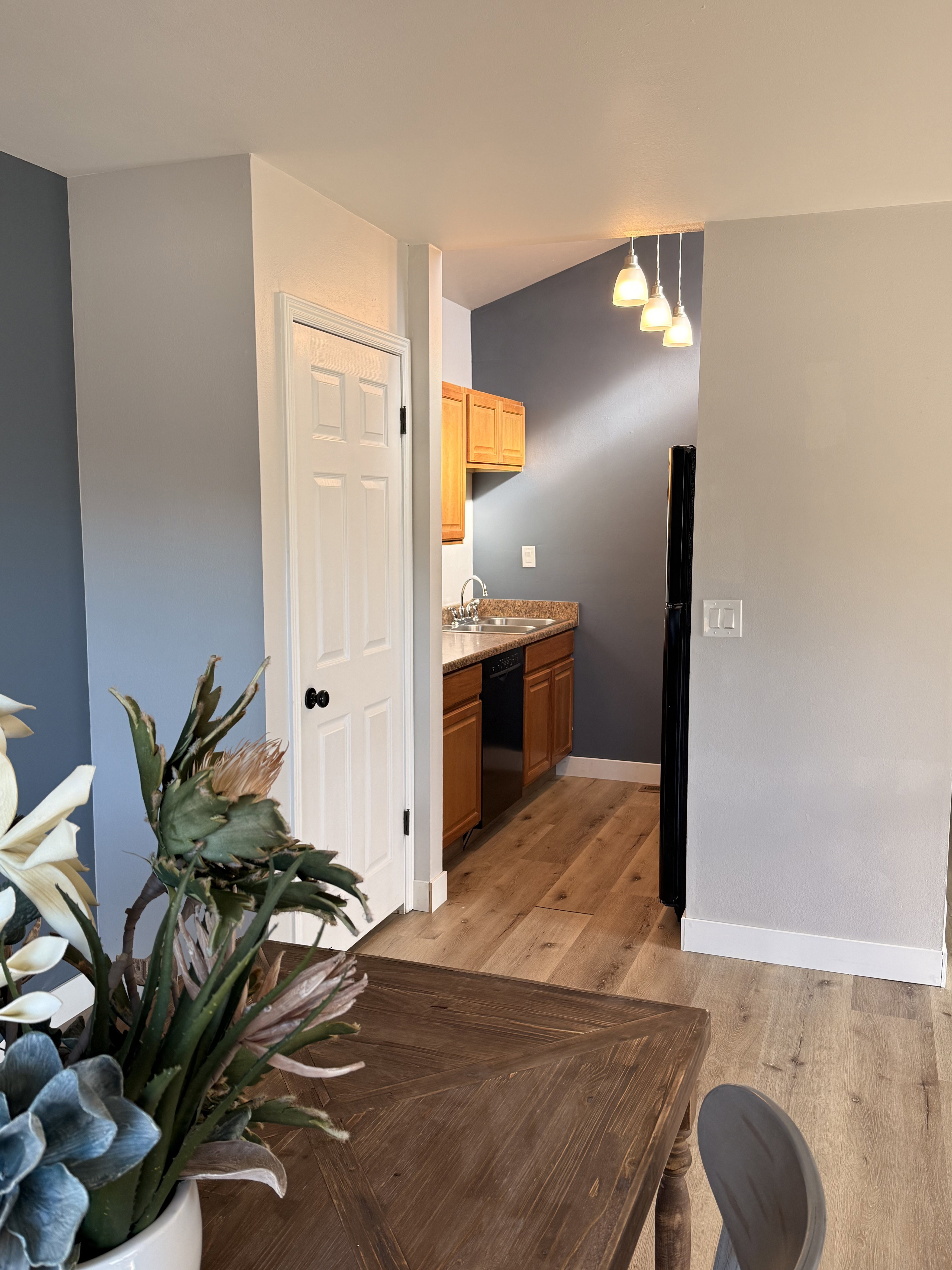 Kitchenette featuring honey-toned cabinetry, a stainless steel sink, black appliances, and a light wood-finish flooring