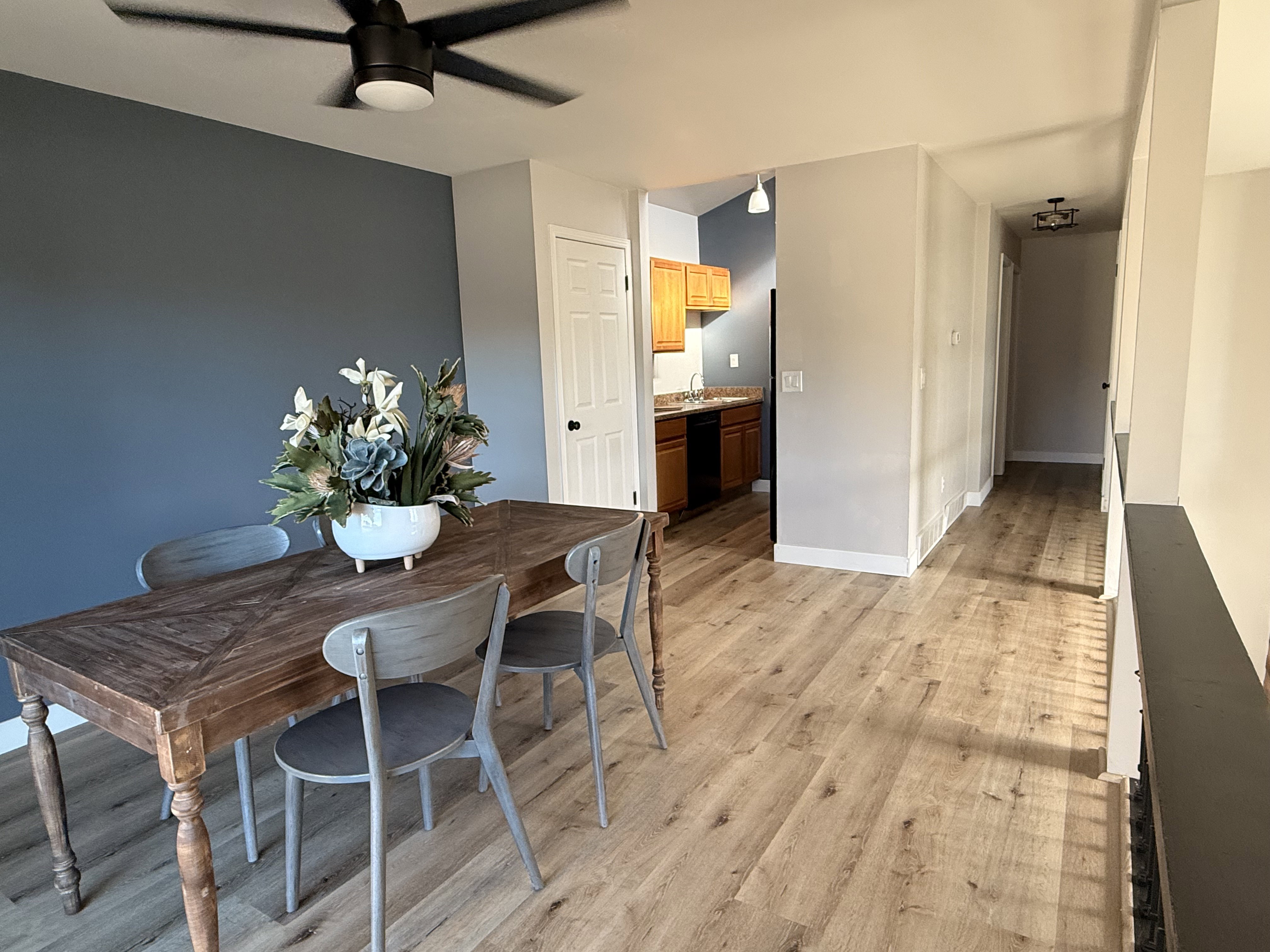 Open concept dining area featuring wood-finish flooring, a contemporary ceiling fan, and a painted accent wall
