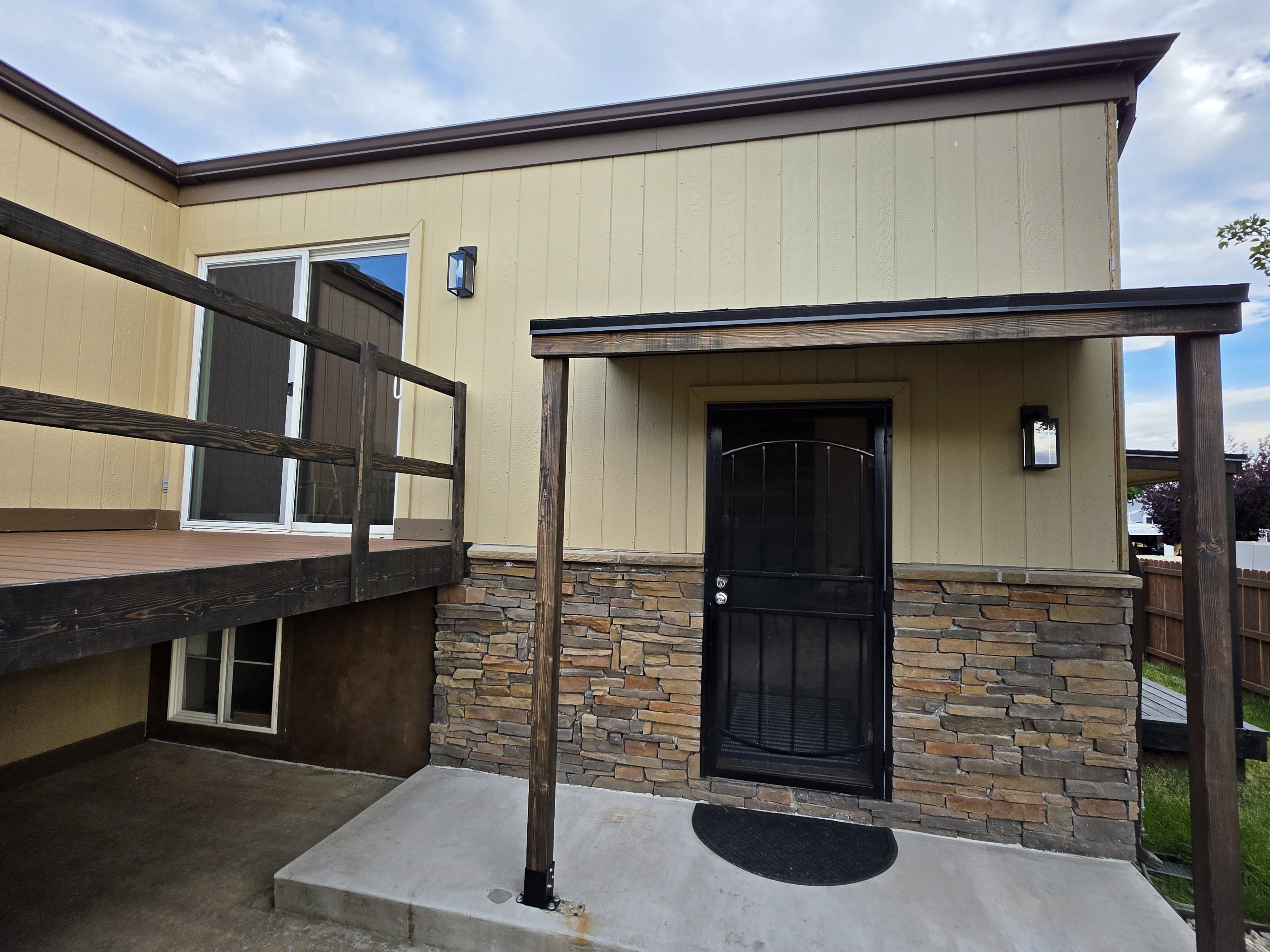 Exterior featuring horizontal siding, stone veneer accents, and a covered entry with a security door