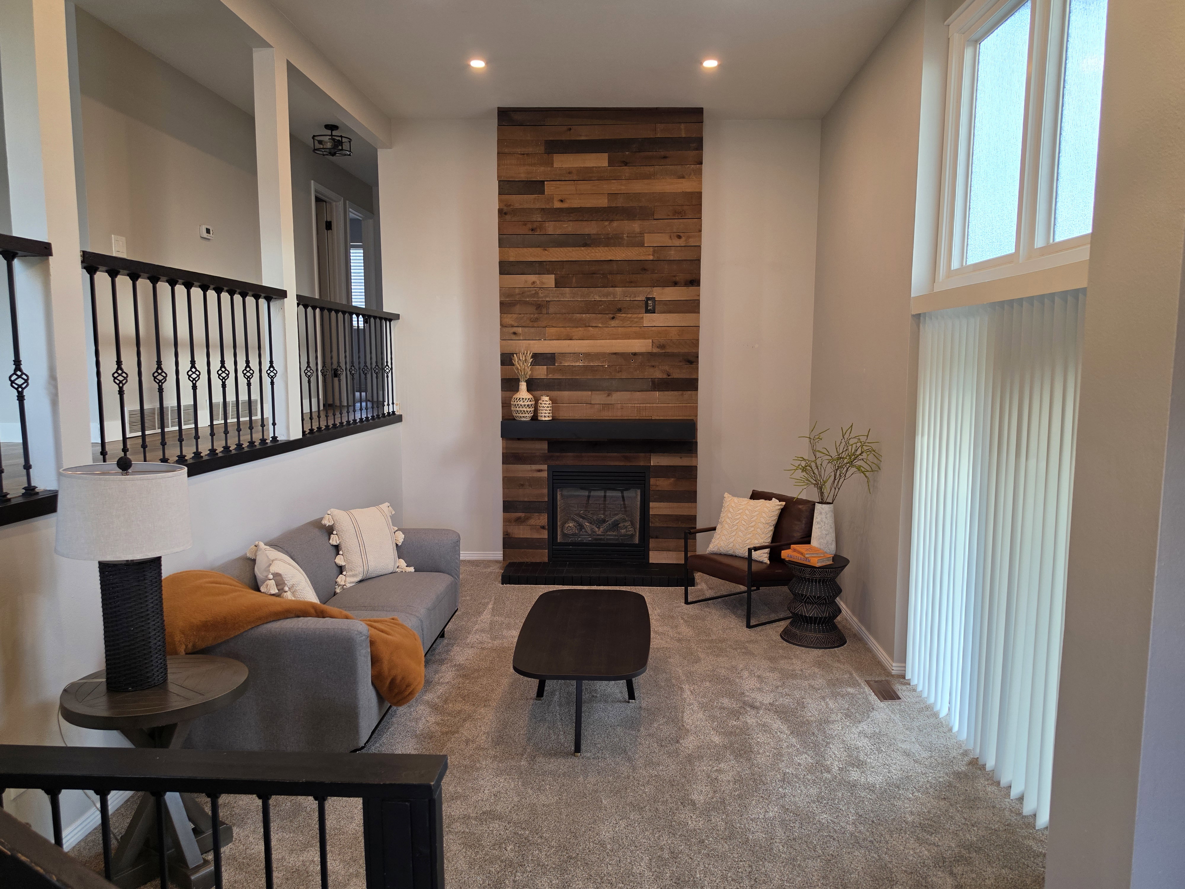 Living area featuring a floor-to-ceiling accent wall with horizontal wood paneling, an integrated fireplace with a dark mantel, and recessed ceiling lighting