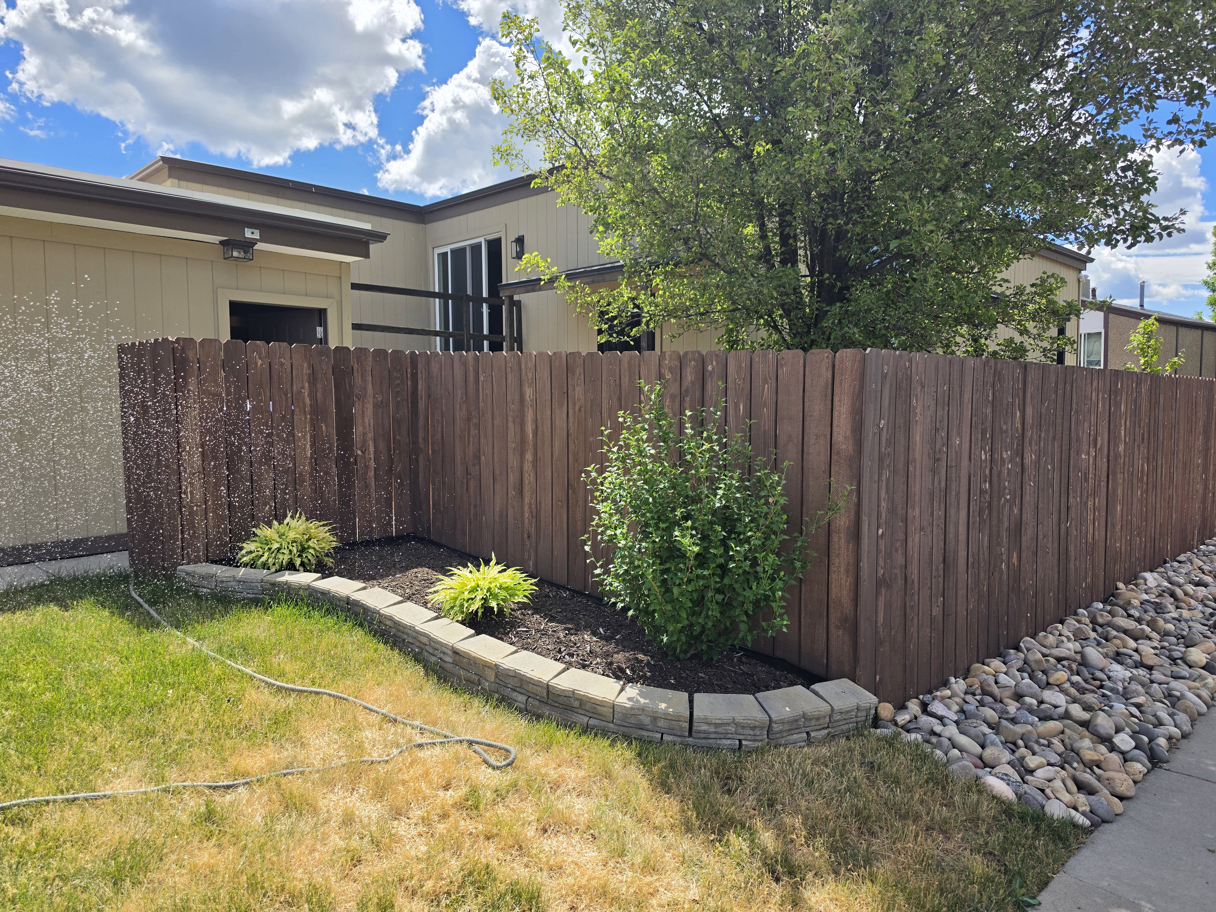 Wood privacy fence enclosing a landscaped area with decorative rock and plantings