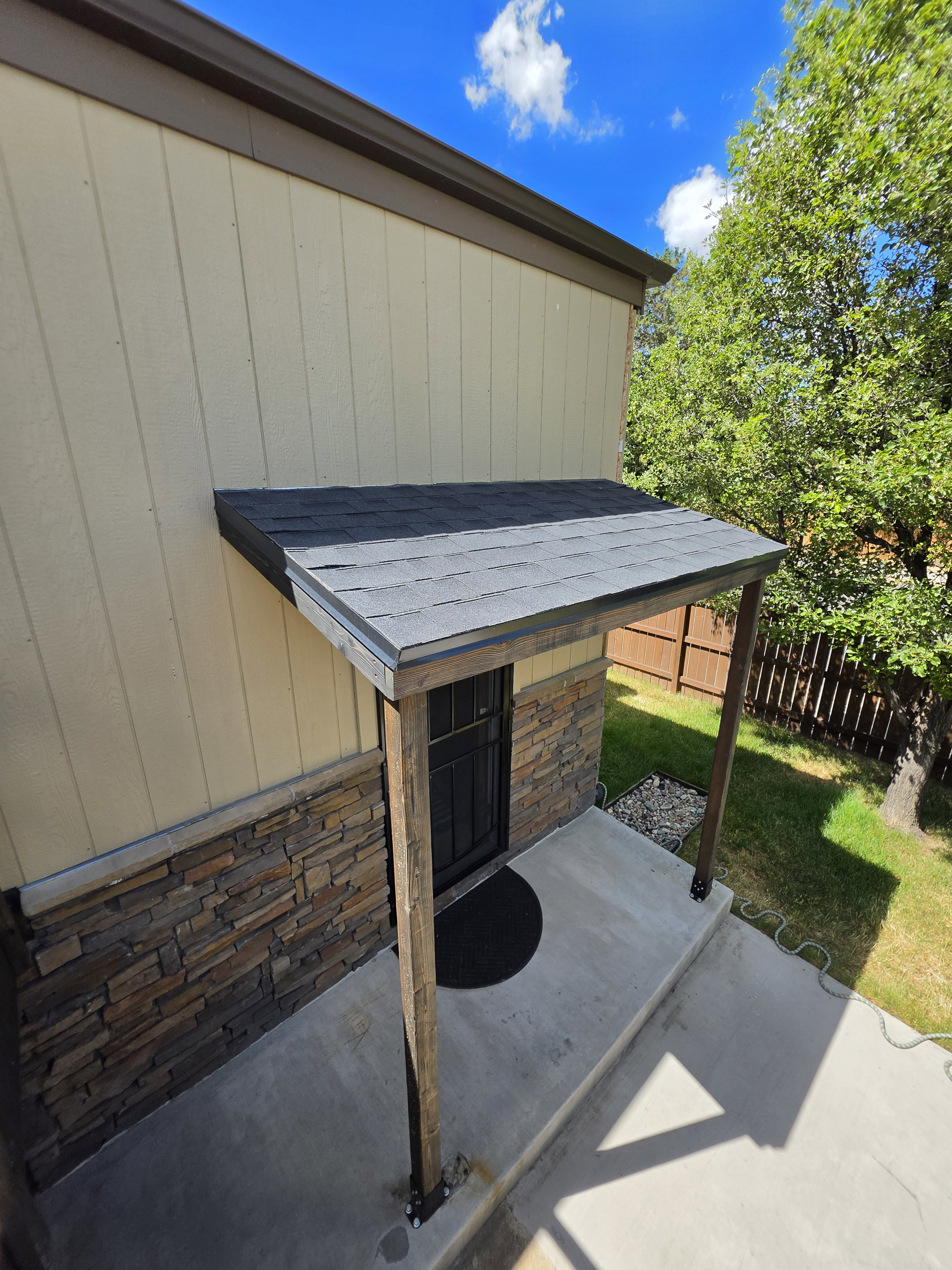 Covered entryway with two-tone architectural shingles and exposed wood support beams
