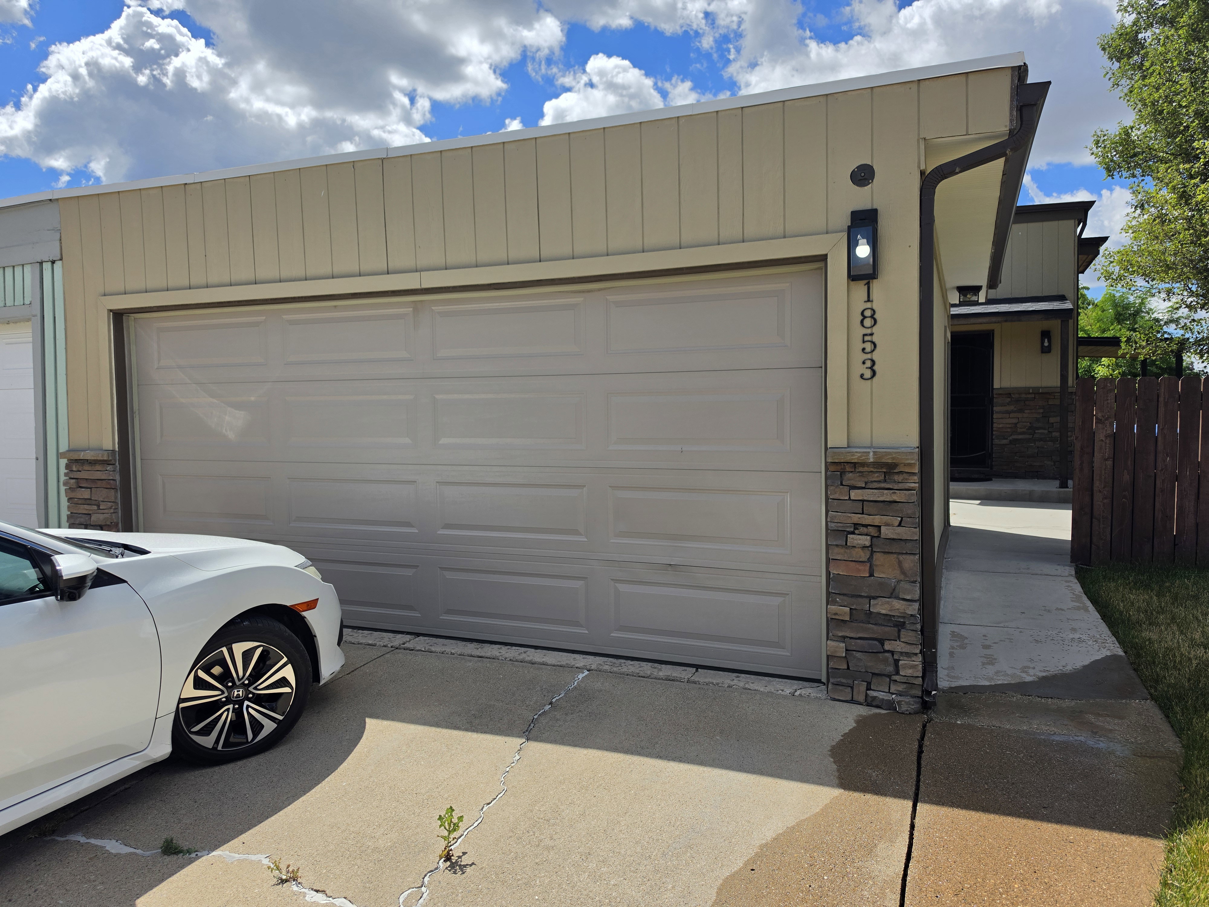 Attached garage with a panel door, complemented by board and batten siding and stacked stone accents