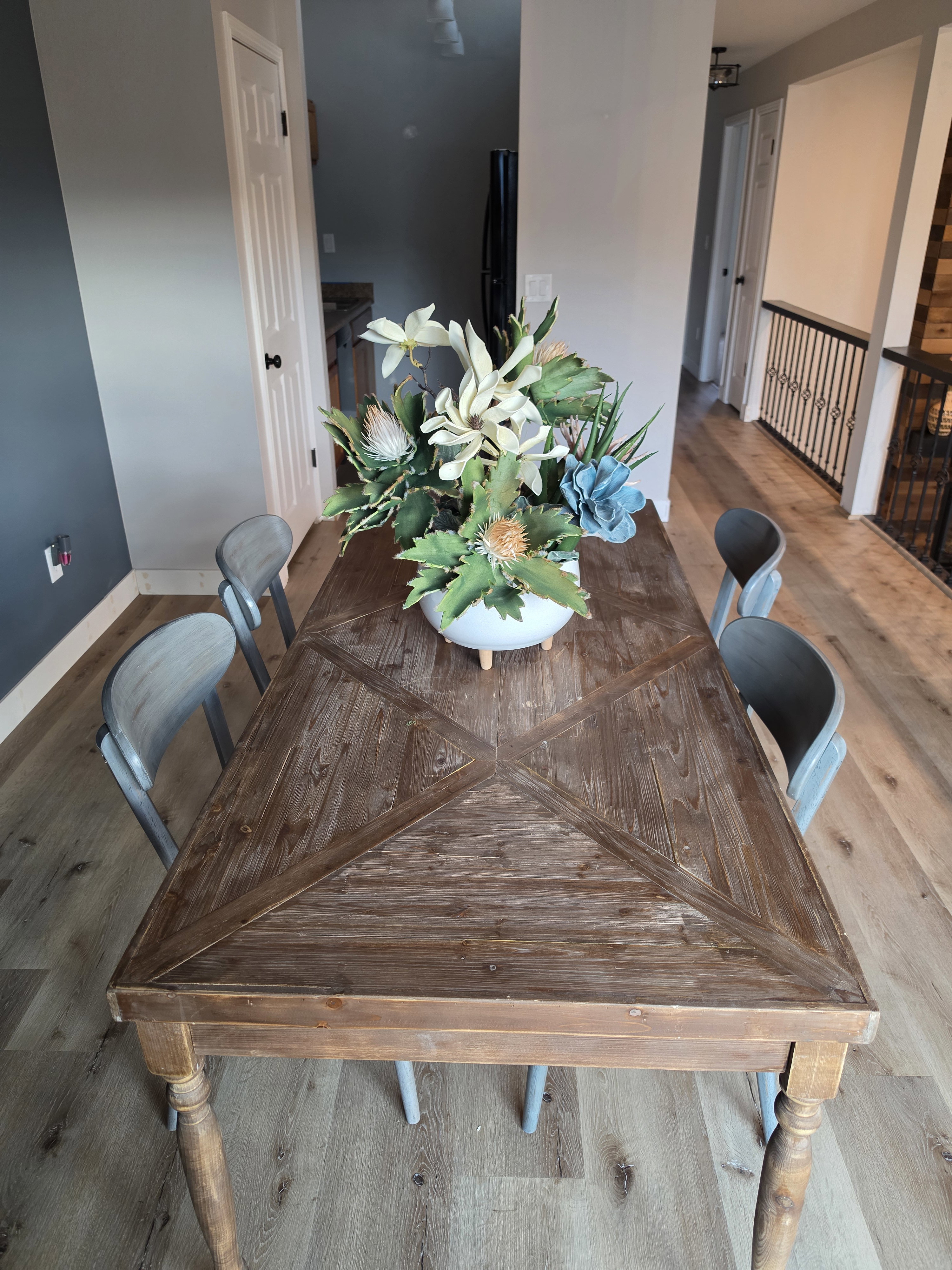 Open-concept dining area featuring wood-finish flooring, a contemporary iron railing, and a wood accent wall