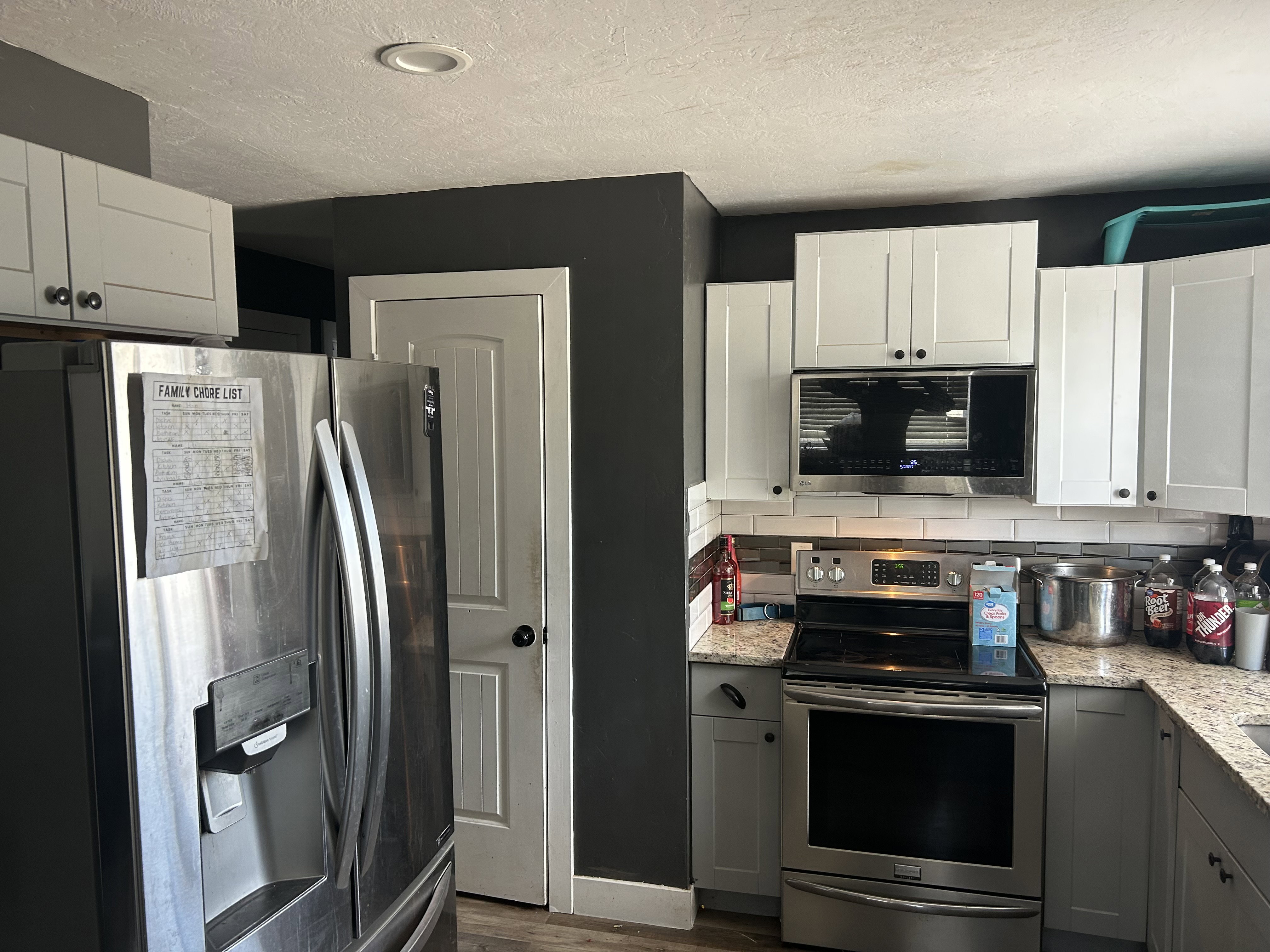 Kitchen featuring stainless steel appliances, white upper cabinetry, and gray lower cabinetry