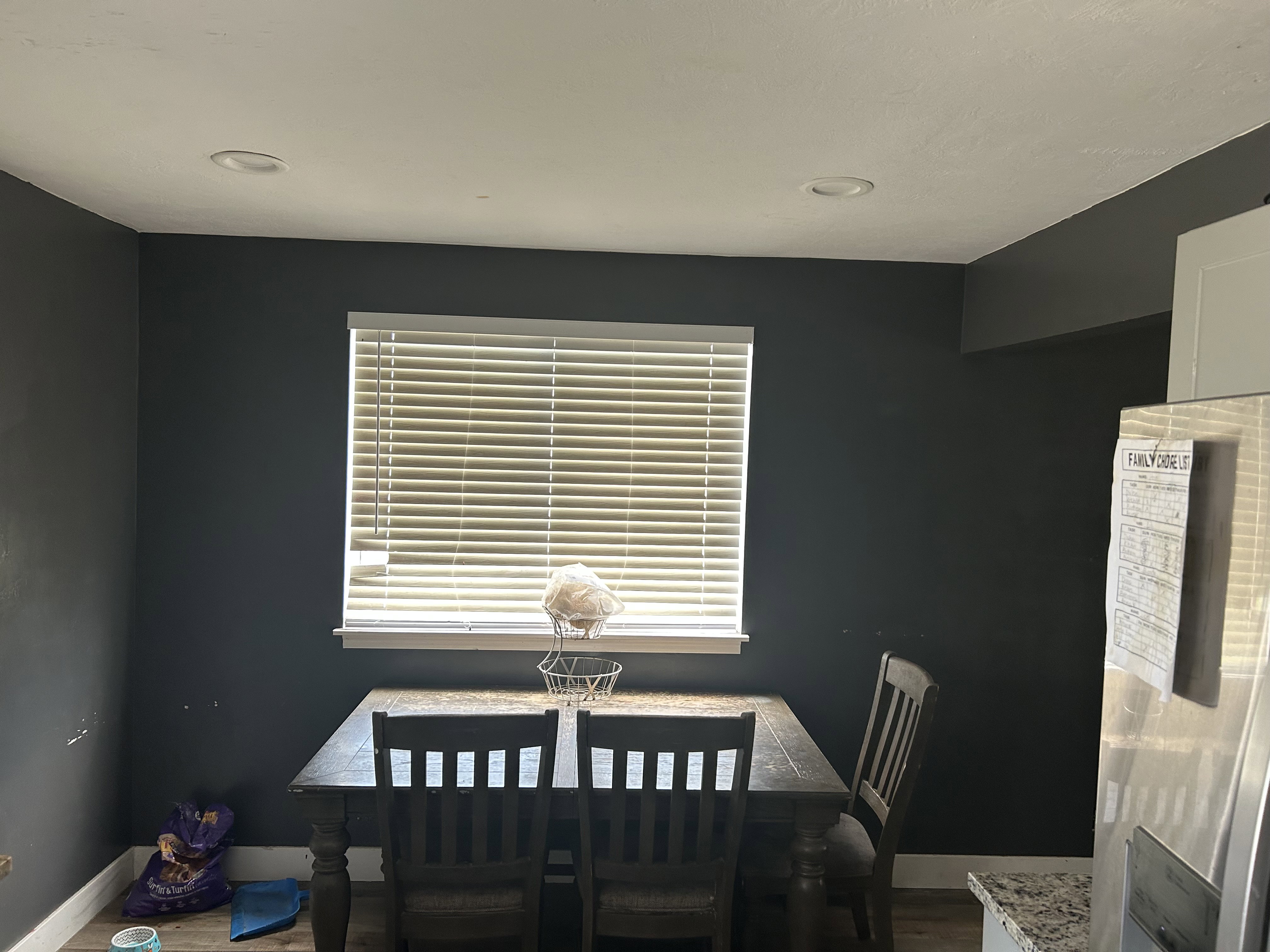 Dining area featuring a window with horizontal blinds, dark walls, and recessed lighting