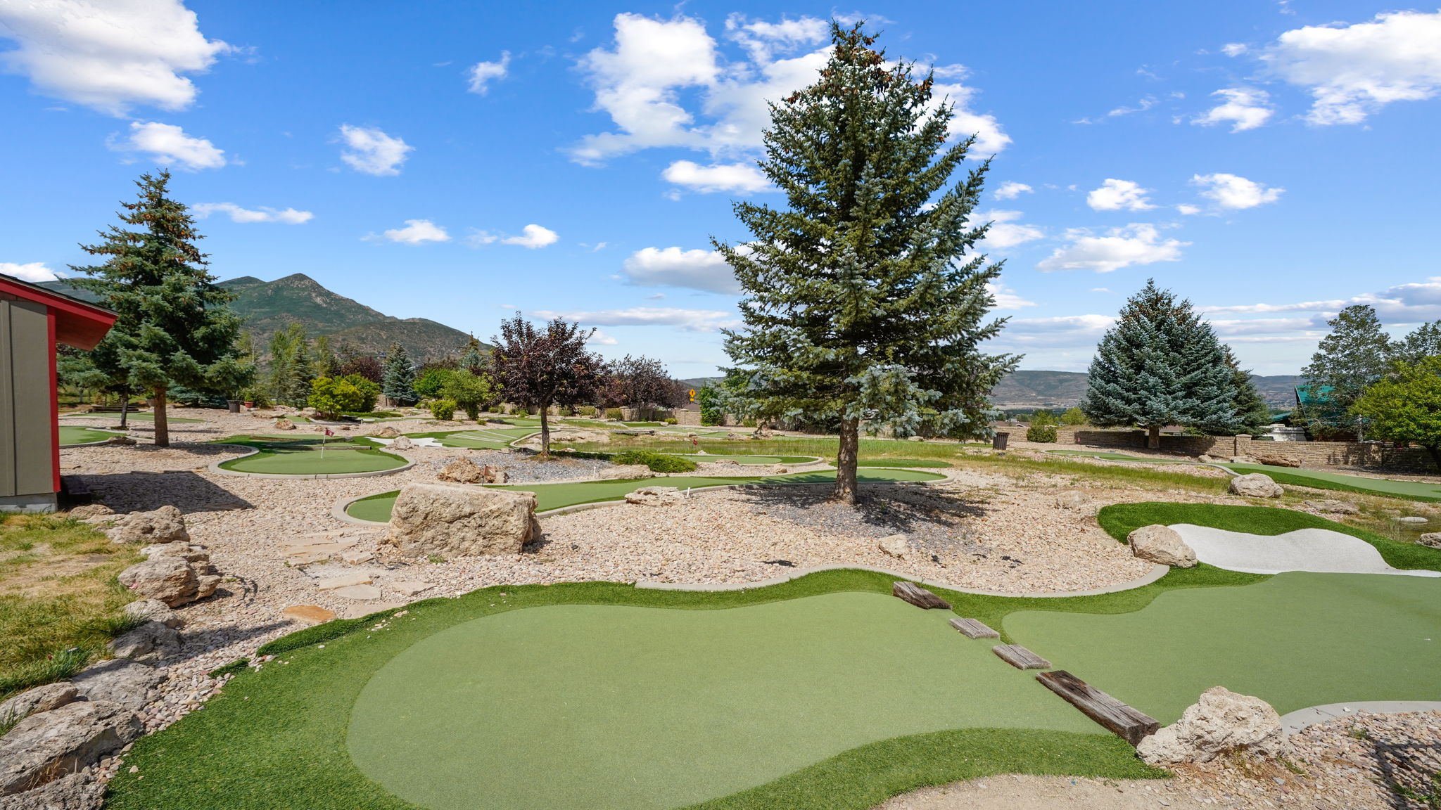 Expansive outdoor space featuring a multi-hole putting green with sand traps and stone accents