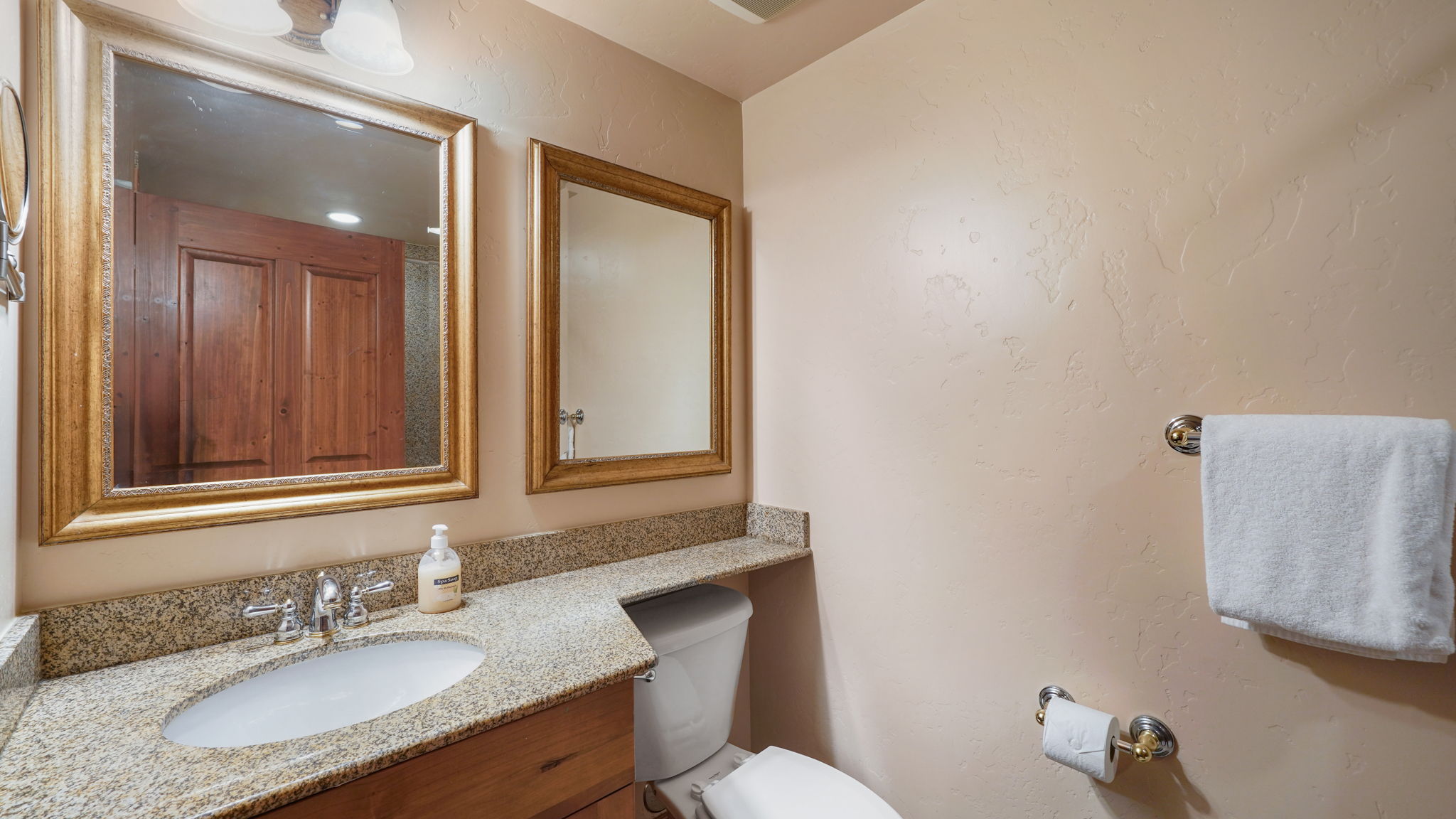 Second bathroom featuring a polished countertop, undermount sink, and dual framed mirrors