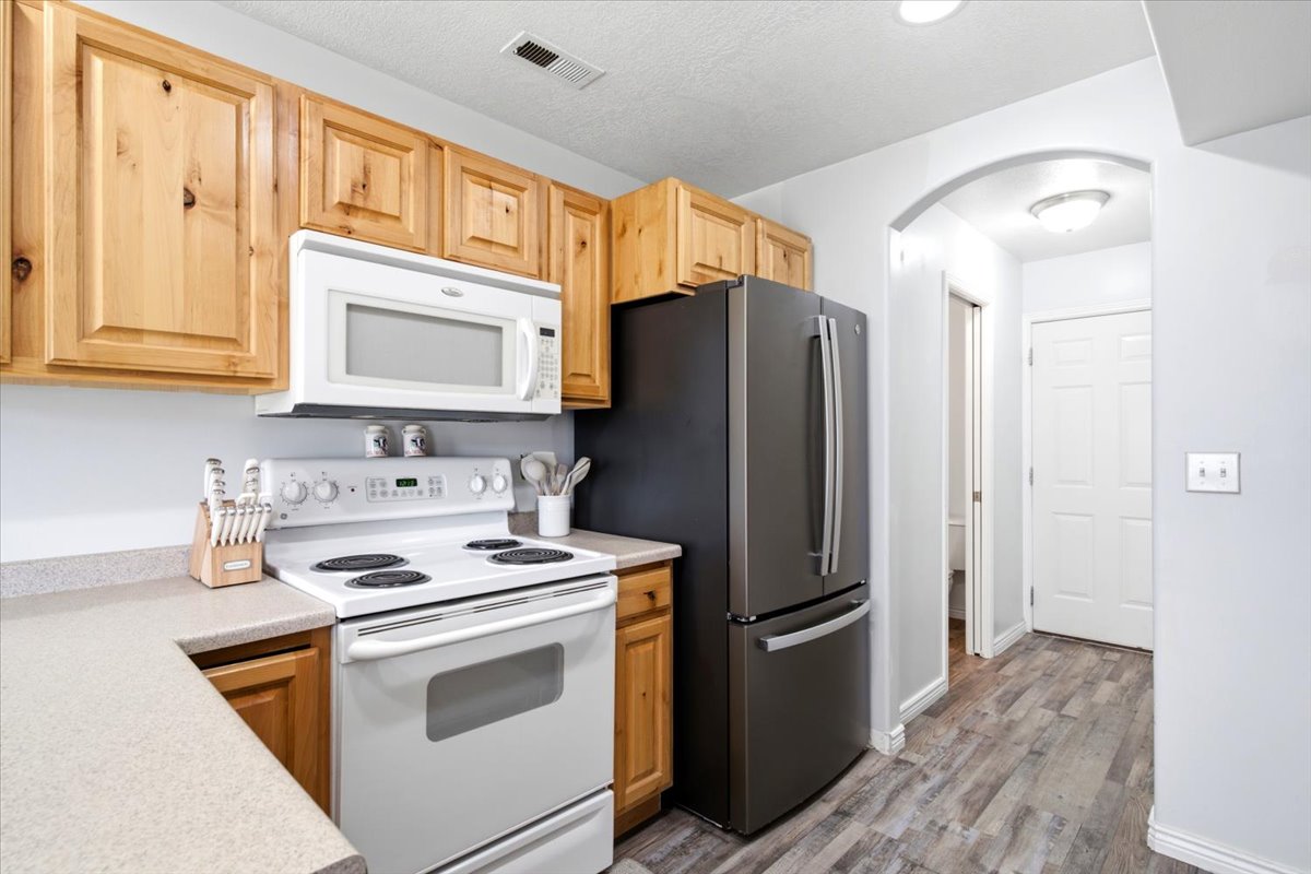 Kitchen featuring wood cabinetry, light-toned countertops, and wood-finish flooring