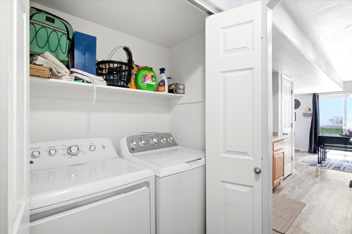 Dedicated laundry closet featuring a top-load washer and dryer, integrated shelving, and a bright white finish