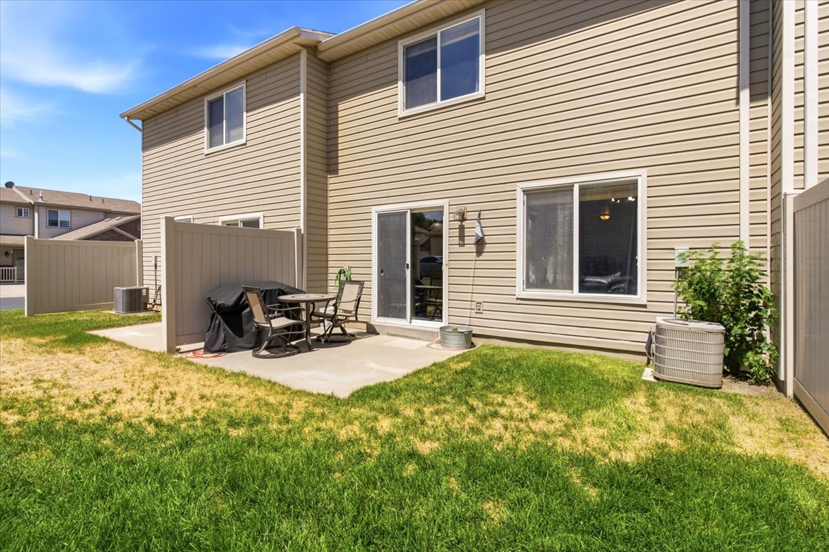 Rear exterior featuring tan horizontal siding and a concrete patio