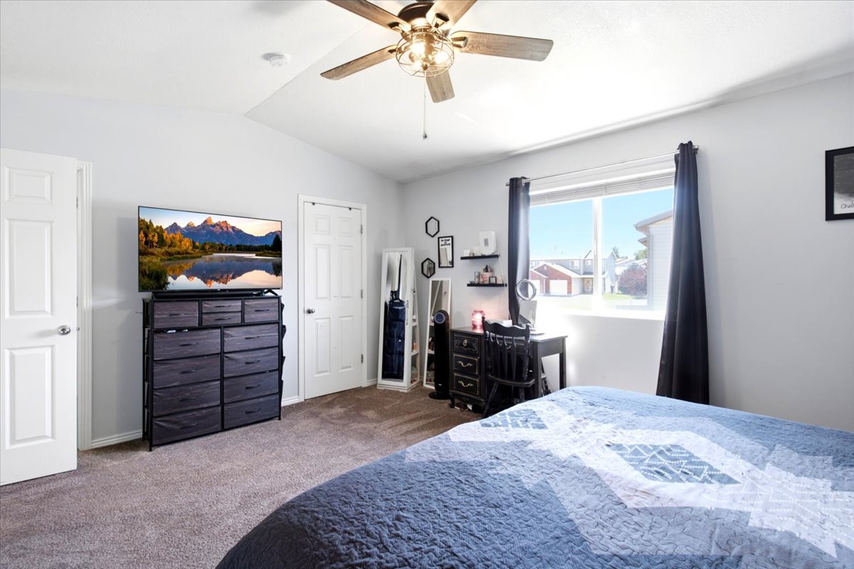 Carpeted room with a ceiling fan, two panel doors, and a window with black curtains