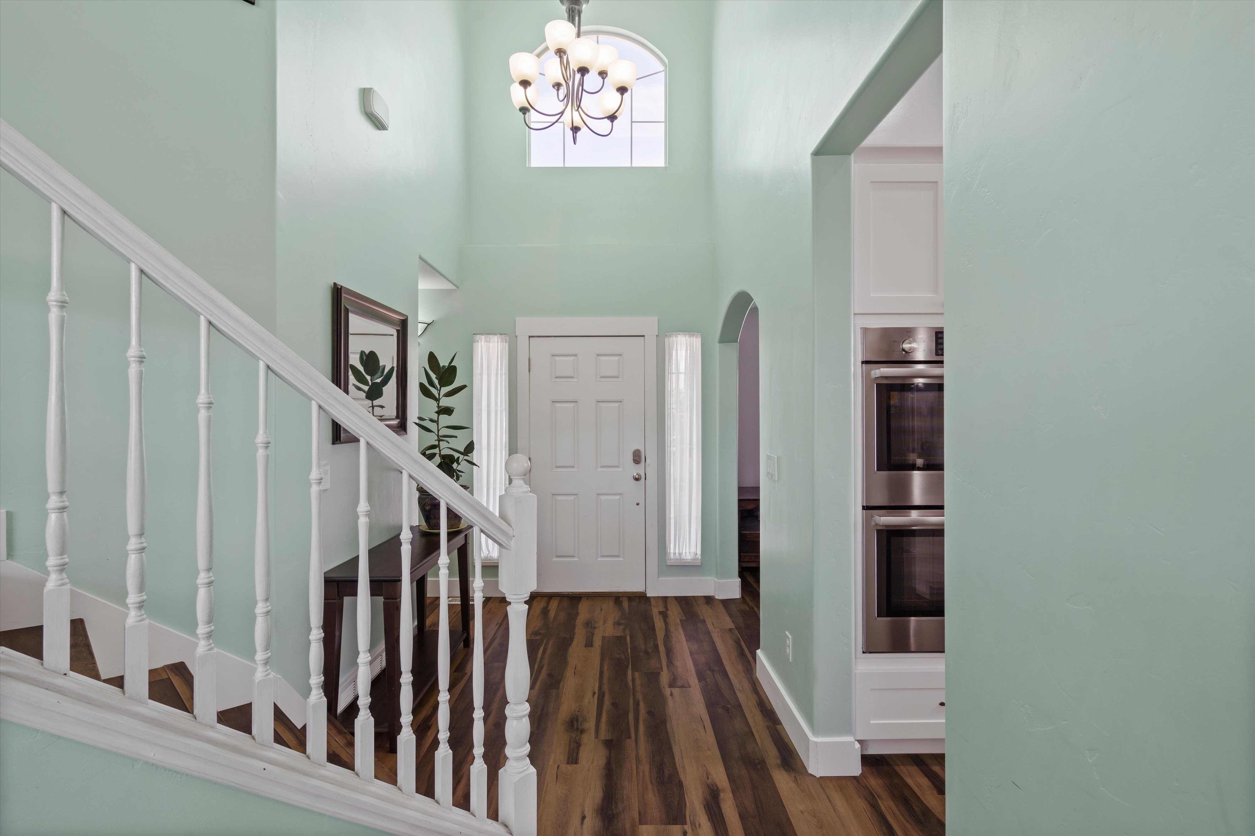 Two-story foyer featuring wood-finish flooring, a white spindle staircase, and a chandelier