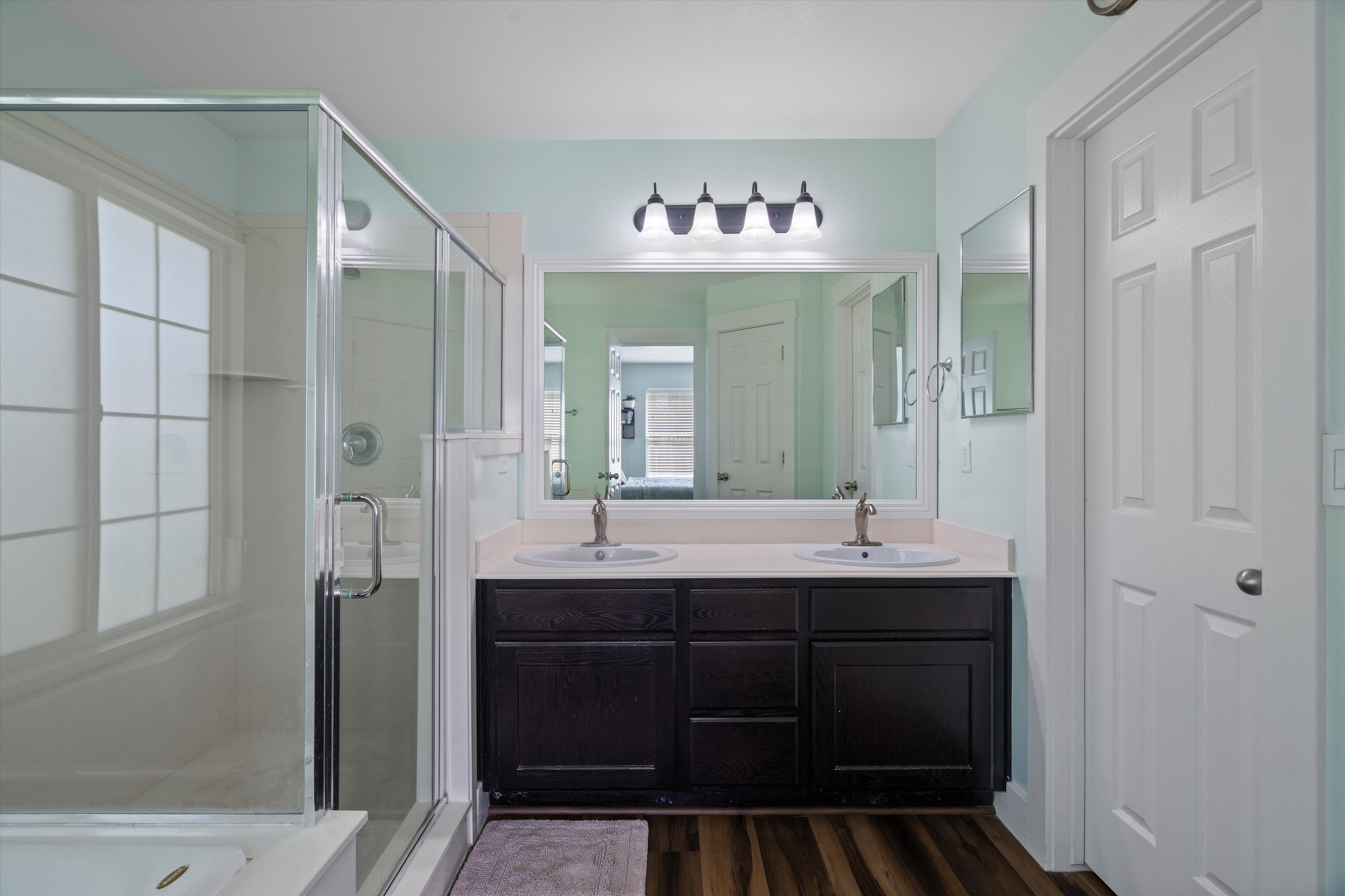Bathroom featuring a dual vanity with dark wood cabinetry, a large framed mirror, and chrome fixtures