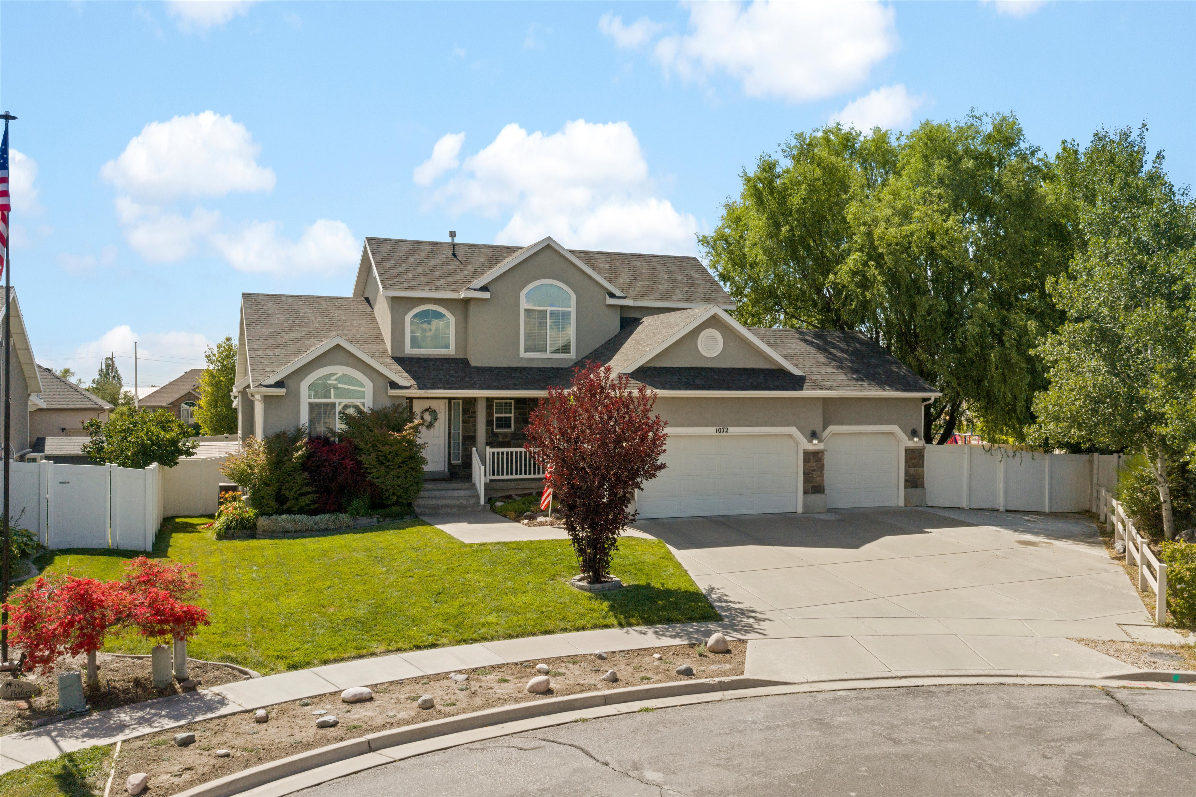Two-story stucco residence featuring a dual-bay garage, arched windows, and mature landscaping